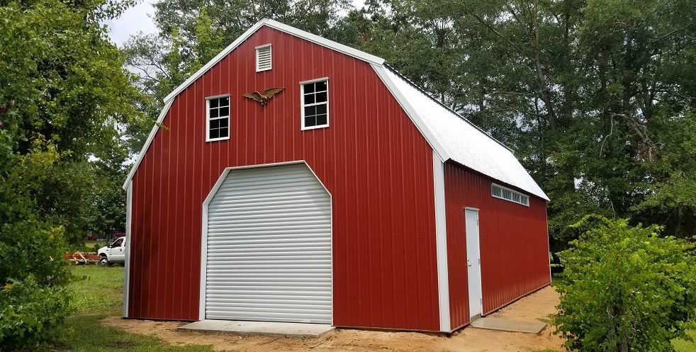 A red barn with a white roof is sitting in the middle of a field.