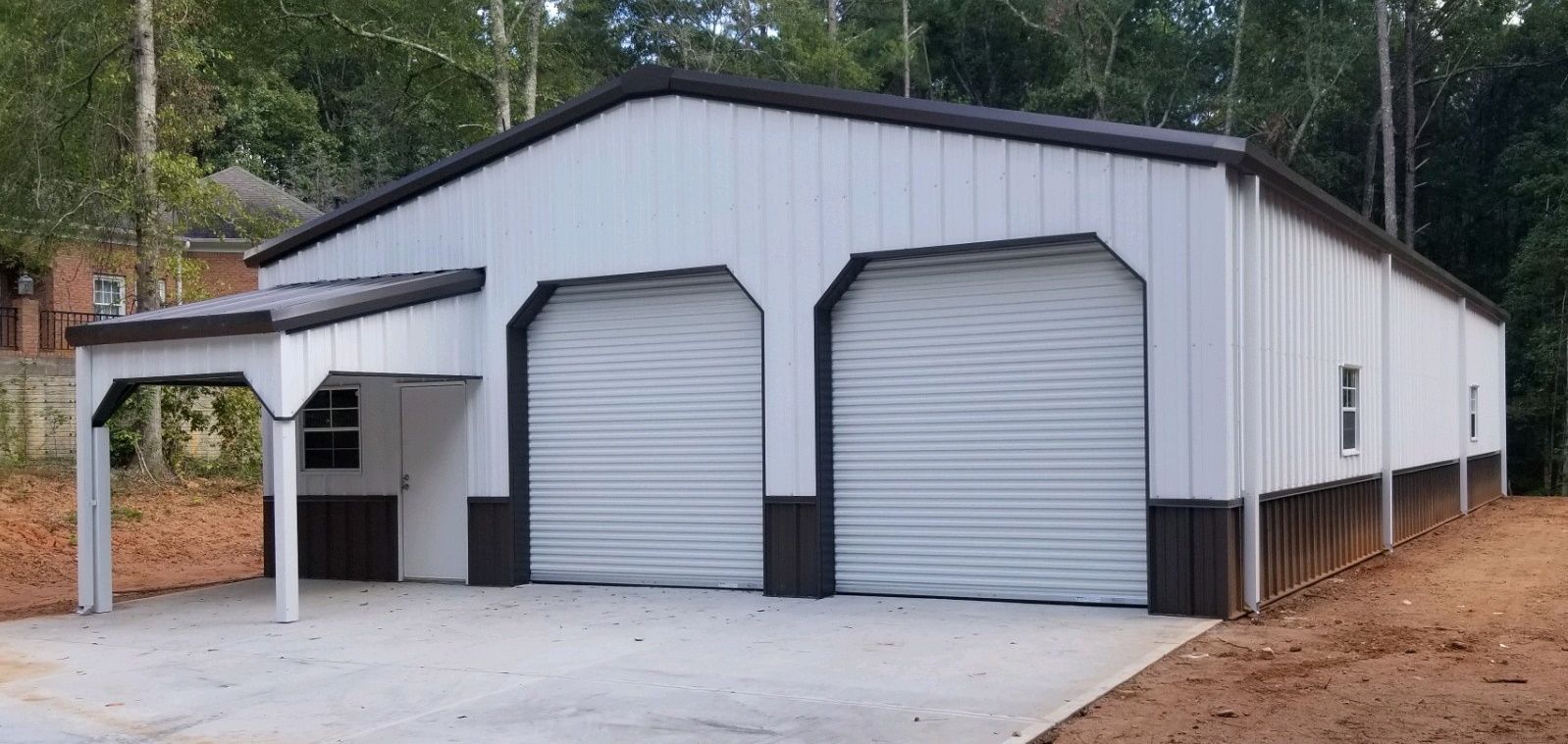 A white and black garage with two garage doors and a porch.
