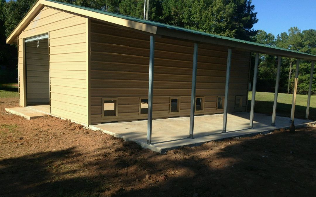 A shed with a green roof is sitting in the middle of a dirt field.