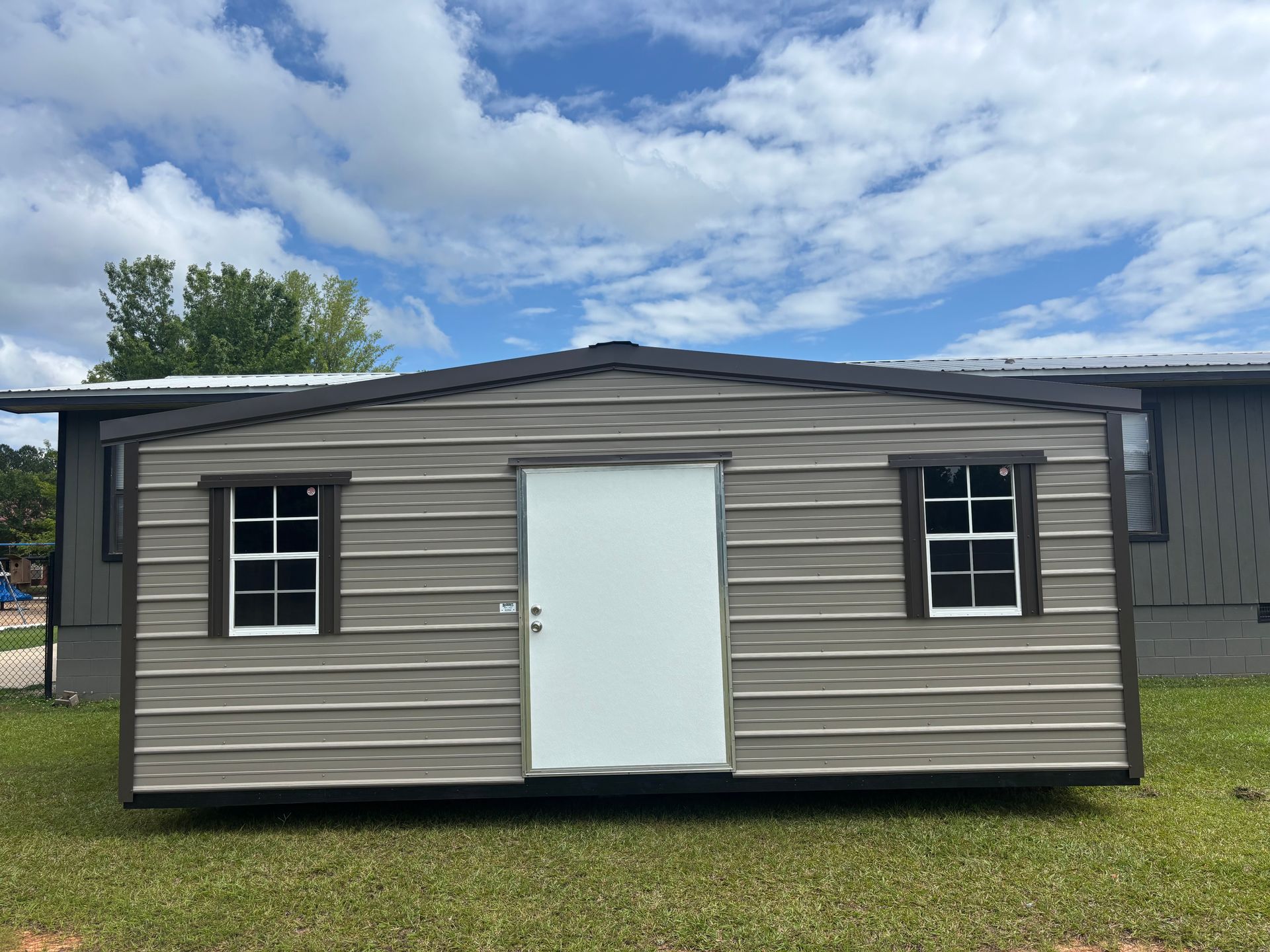 A small house with two windows and a door is sitting on top of a lush green field.