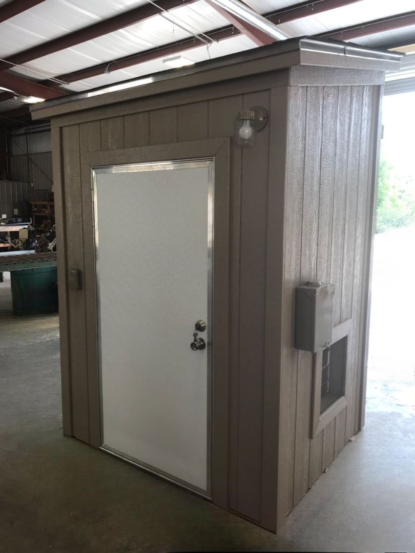 A small shed with a white door is sitting in a garage.