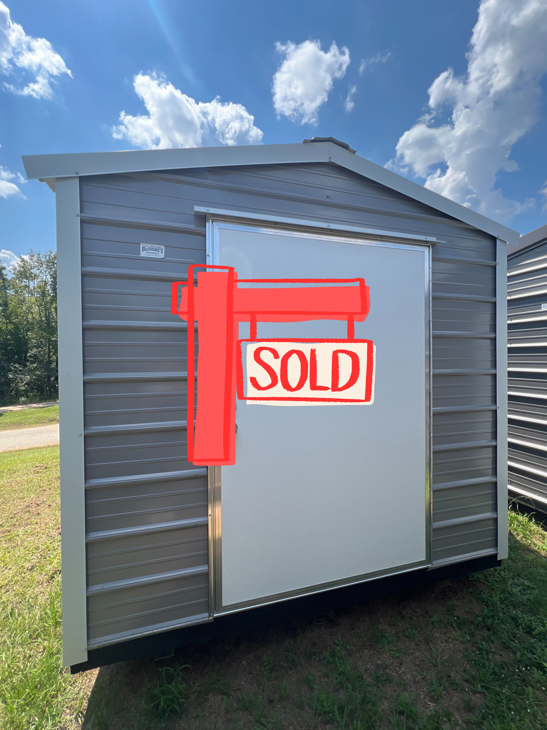 Gray shed with white door, silver trim, and light blue sky background.