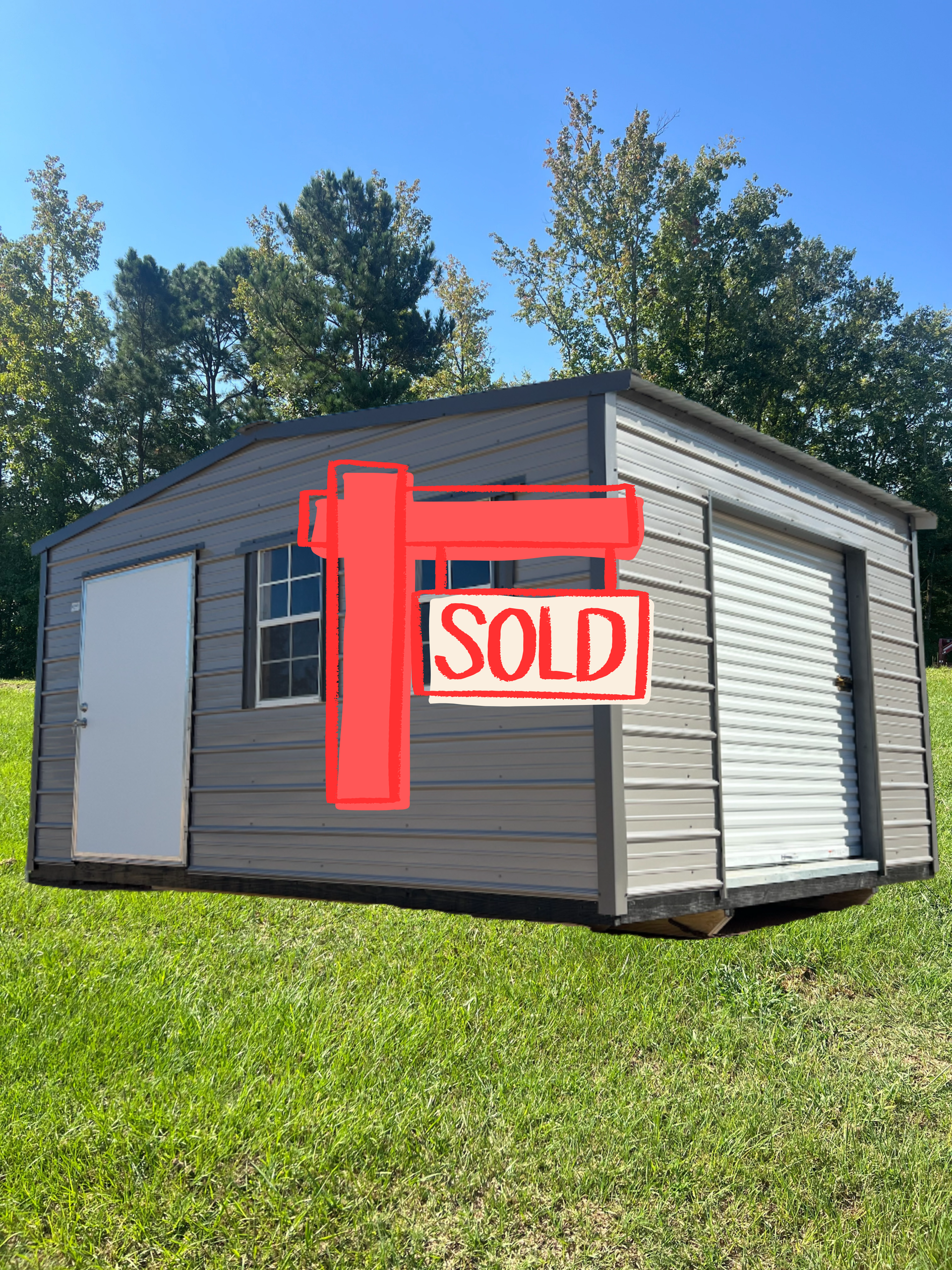 Gray shed with white door, windows, and garage door on green grass under blue sky.