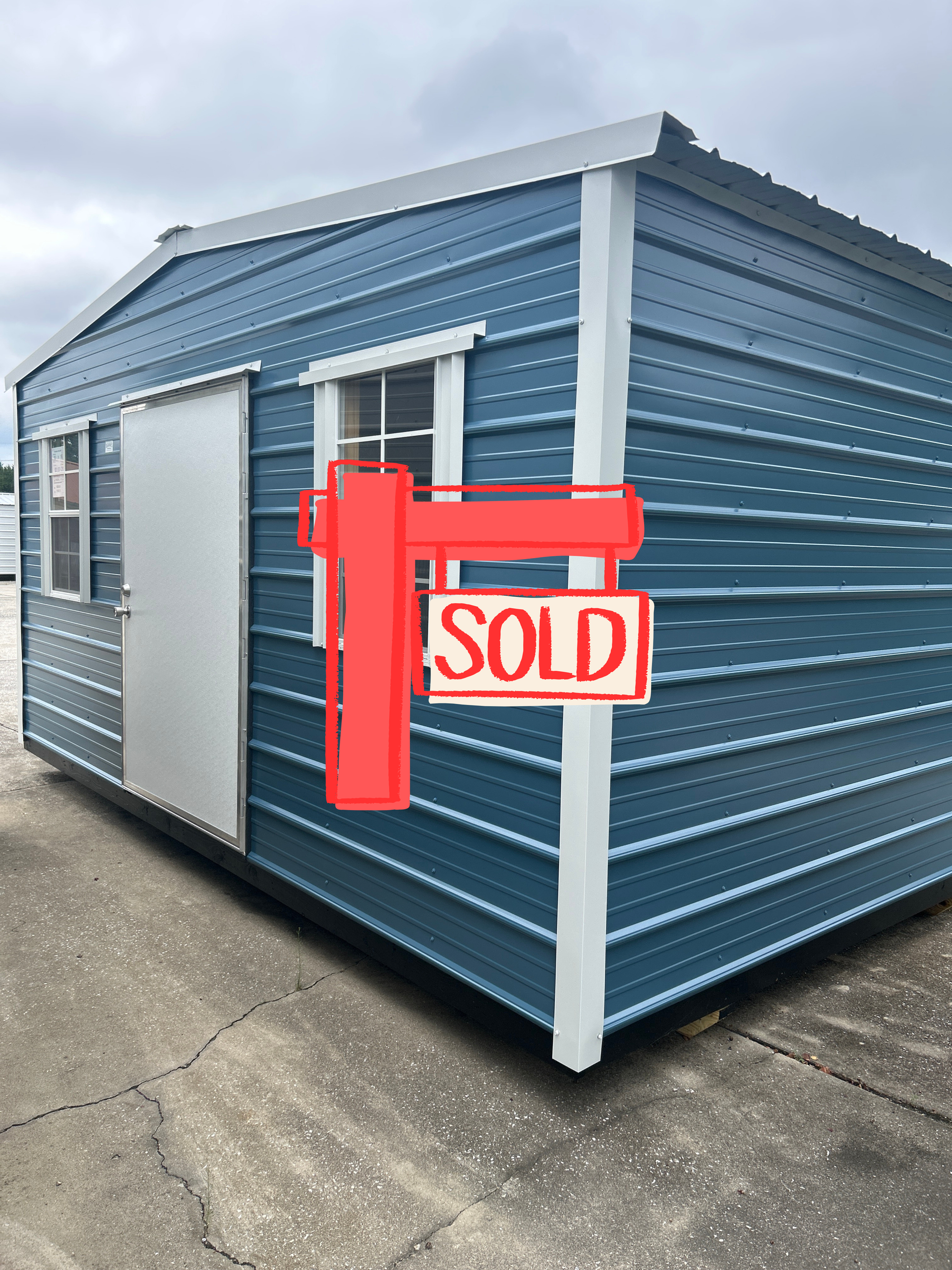Blue storage shed with a red sold sign on the front corner