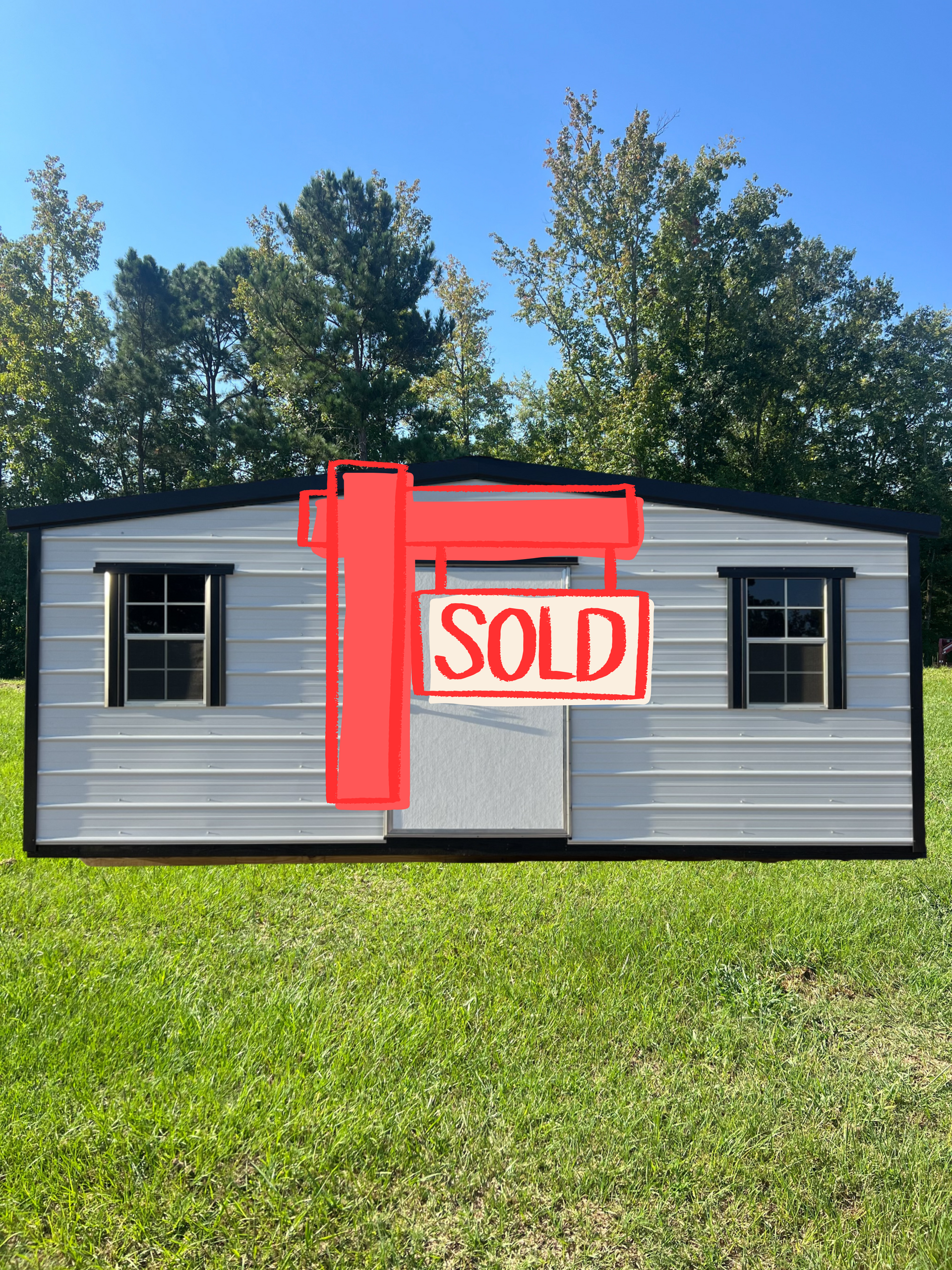 White metal shed with black trim, door, and two windows, set in grassy area.