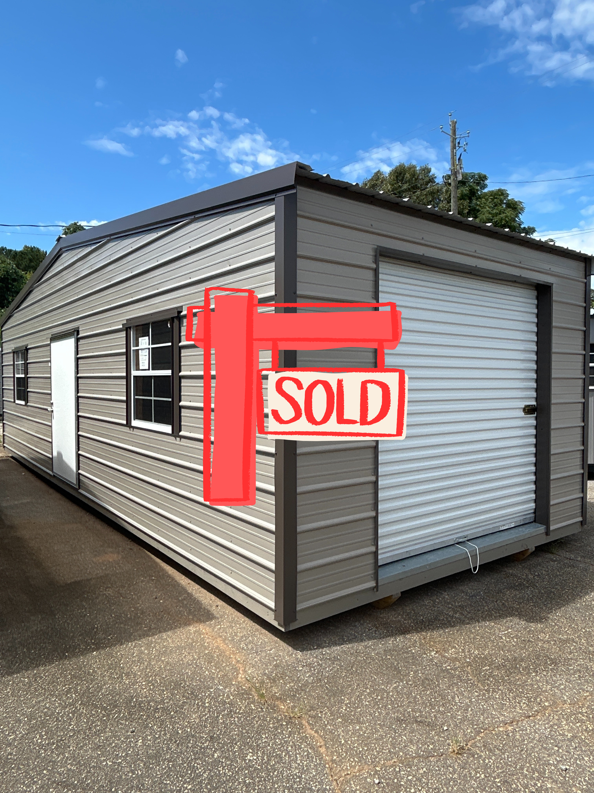 Metal garage with a roll-up door, window, and a side door on a sunny day.