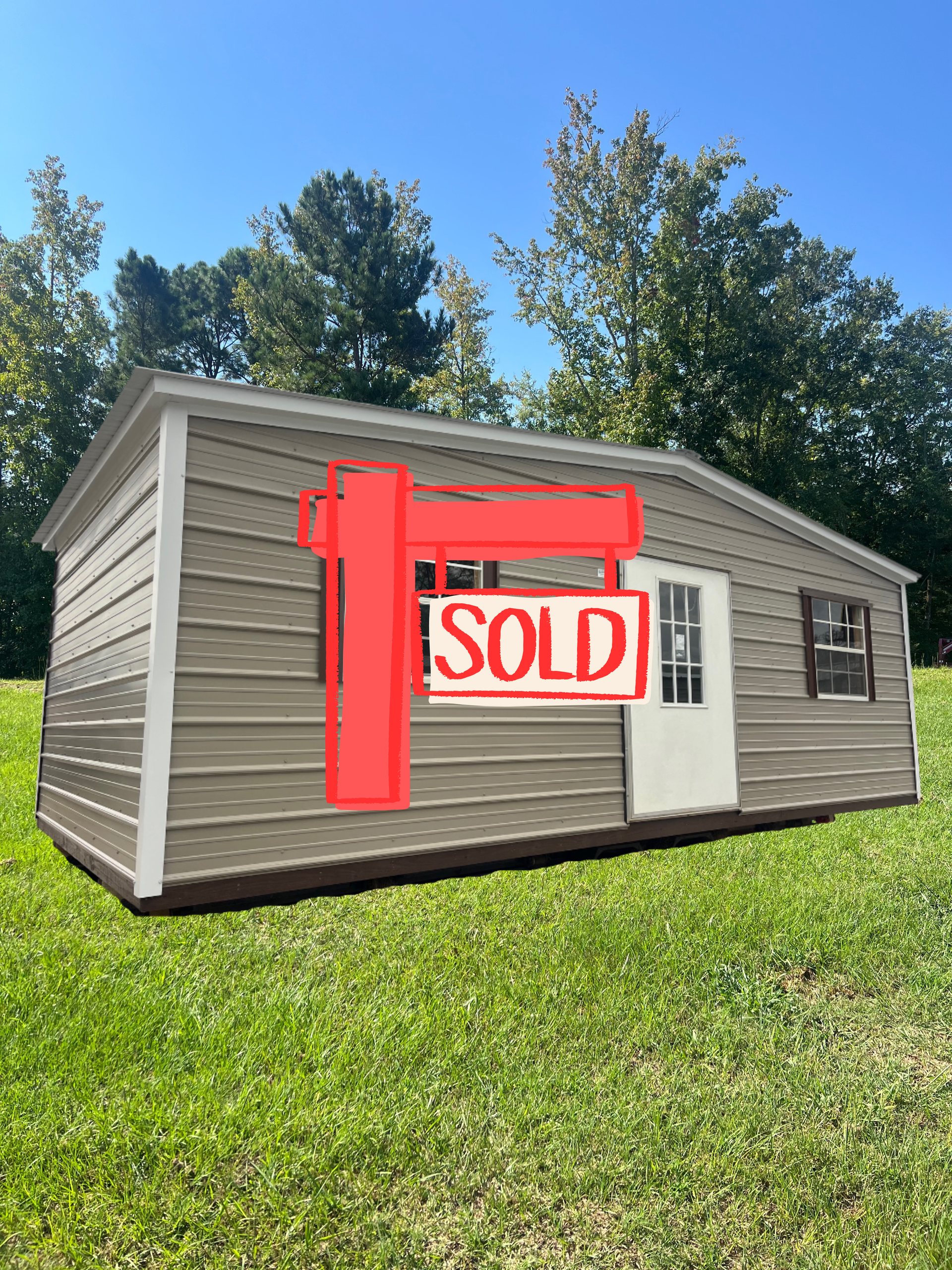 Gray metal shed with white doors and windows, set on gravel.