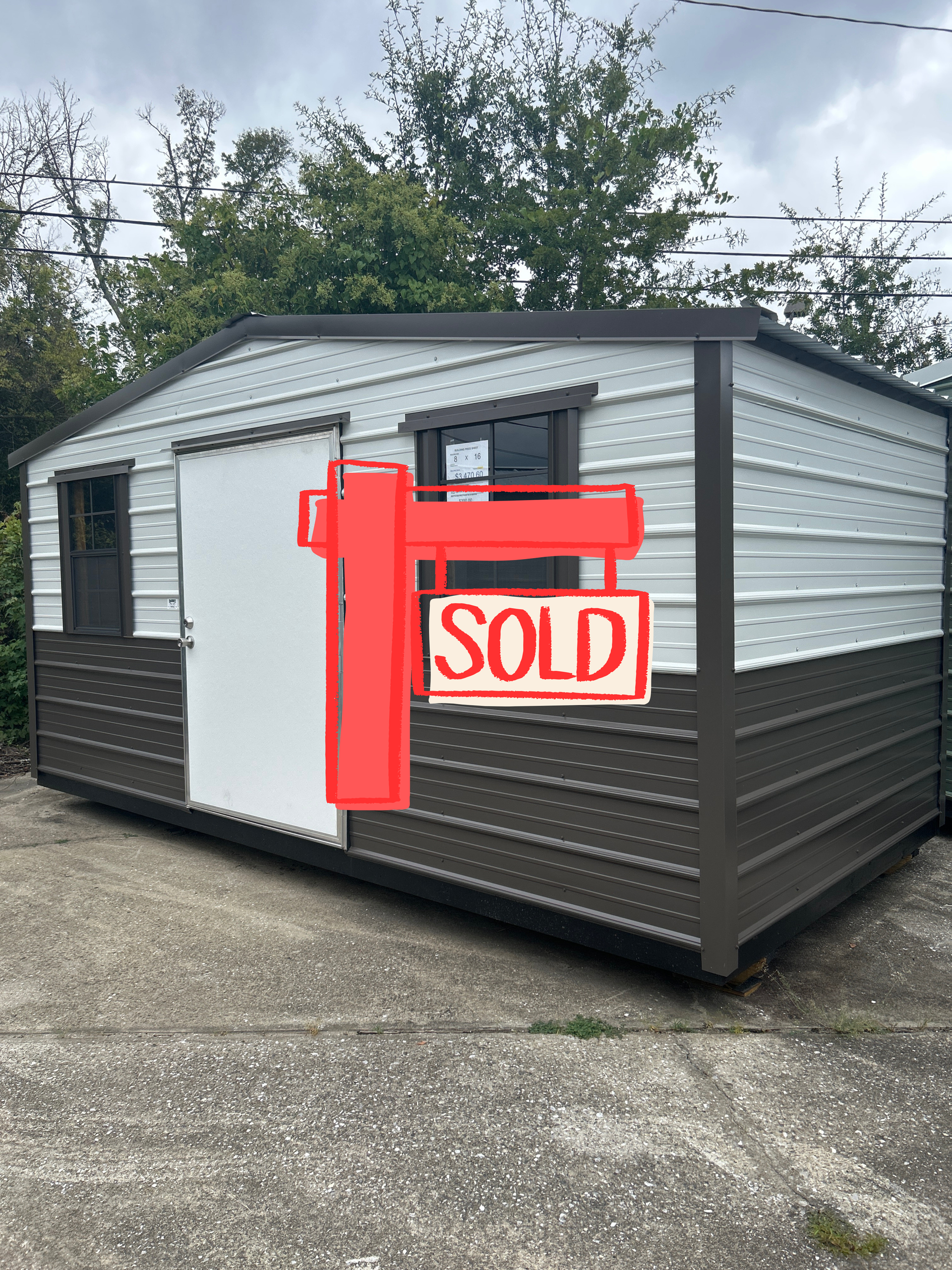 Metal shed with white and brown panels, two windows, and a door on a concrete surface.