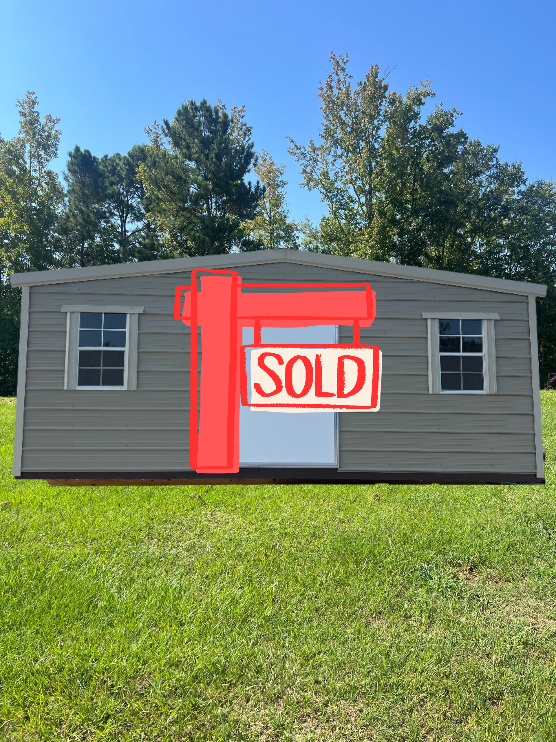 Tan metal shed with white door and windows on green grass.