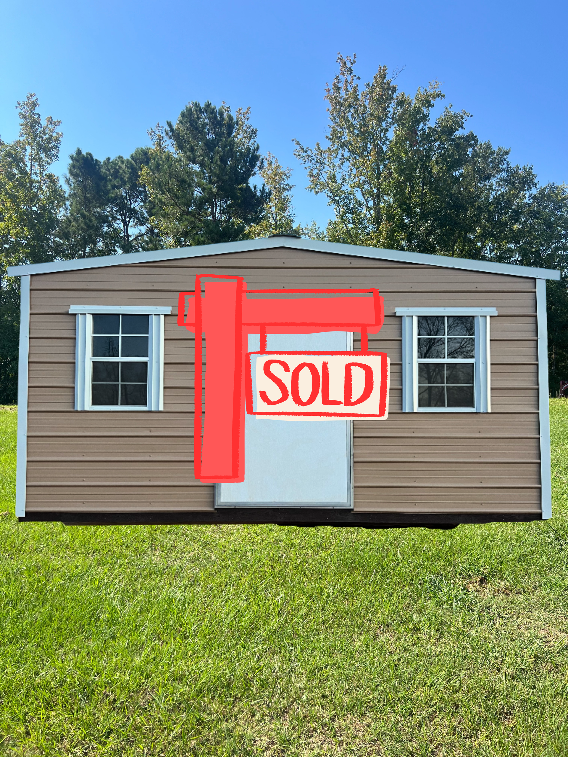 Tan metal shed with white door and windows on a grassy lawn.