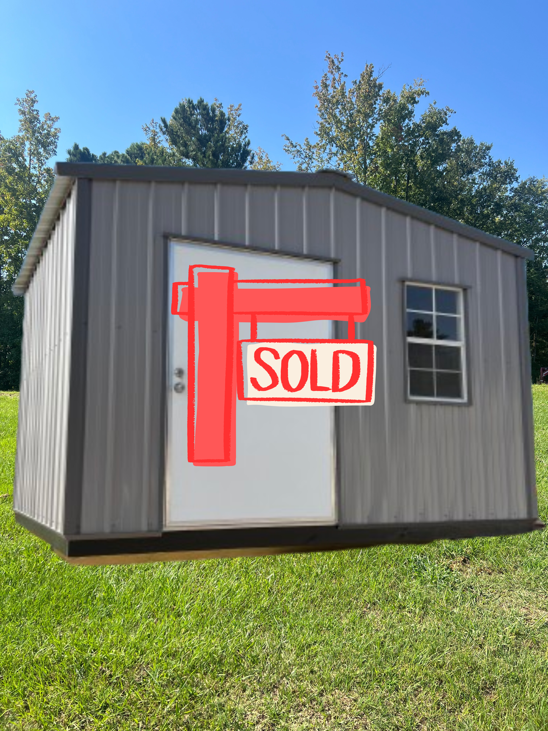 A grey metal storage shed with a single white door and one window, set on a grassy hill under a clear blue sky.