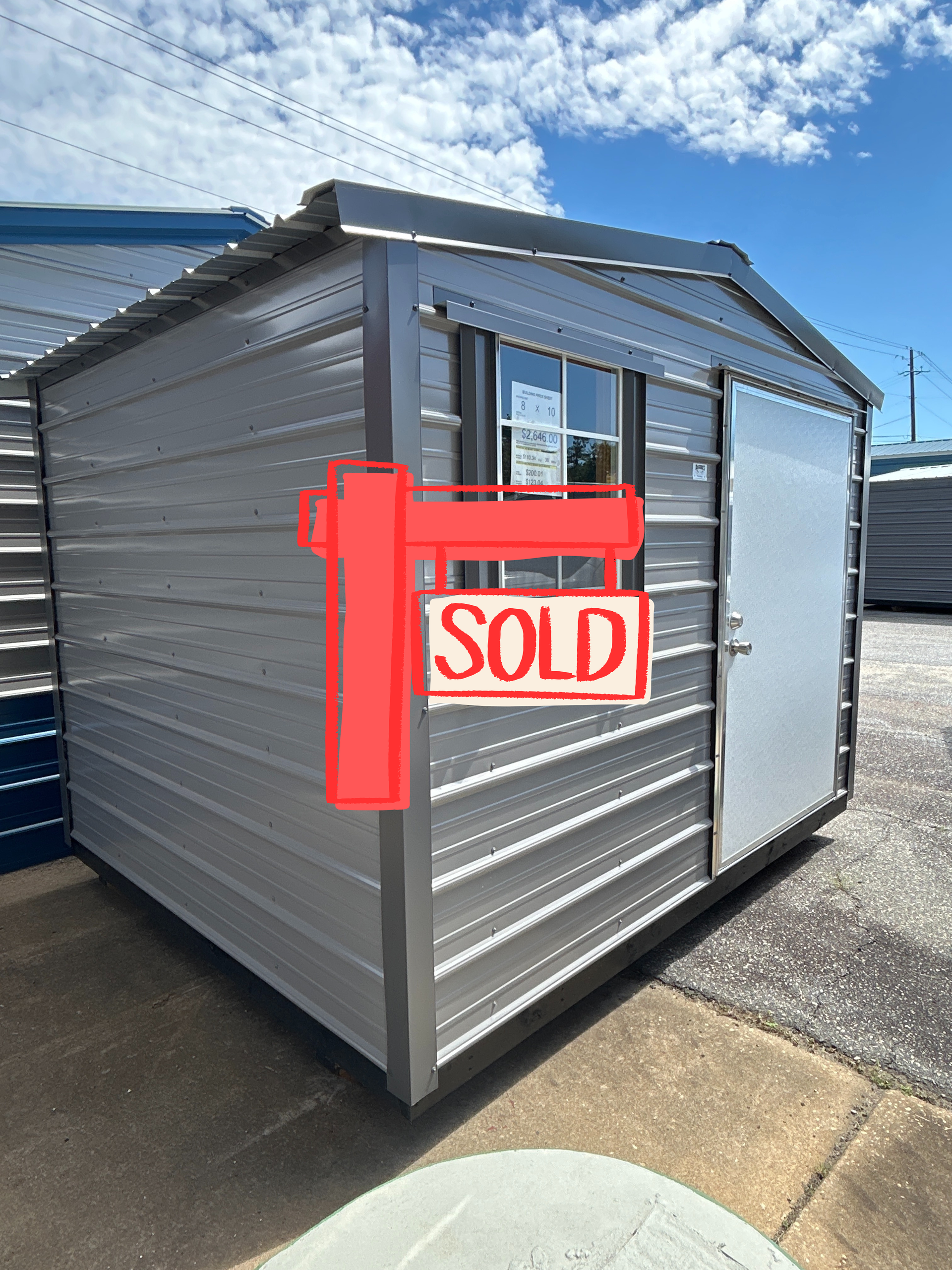 Metal shed with window and door on a brick surface.