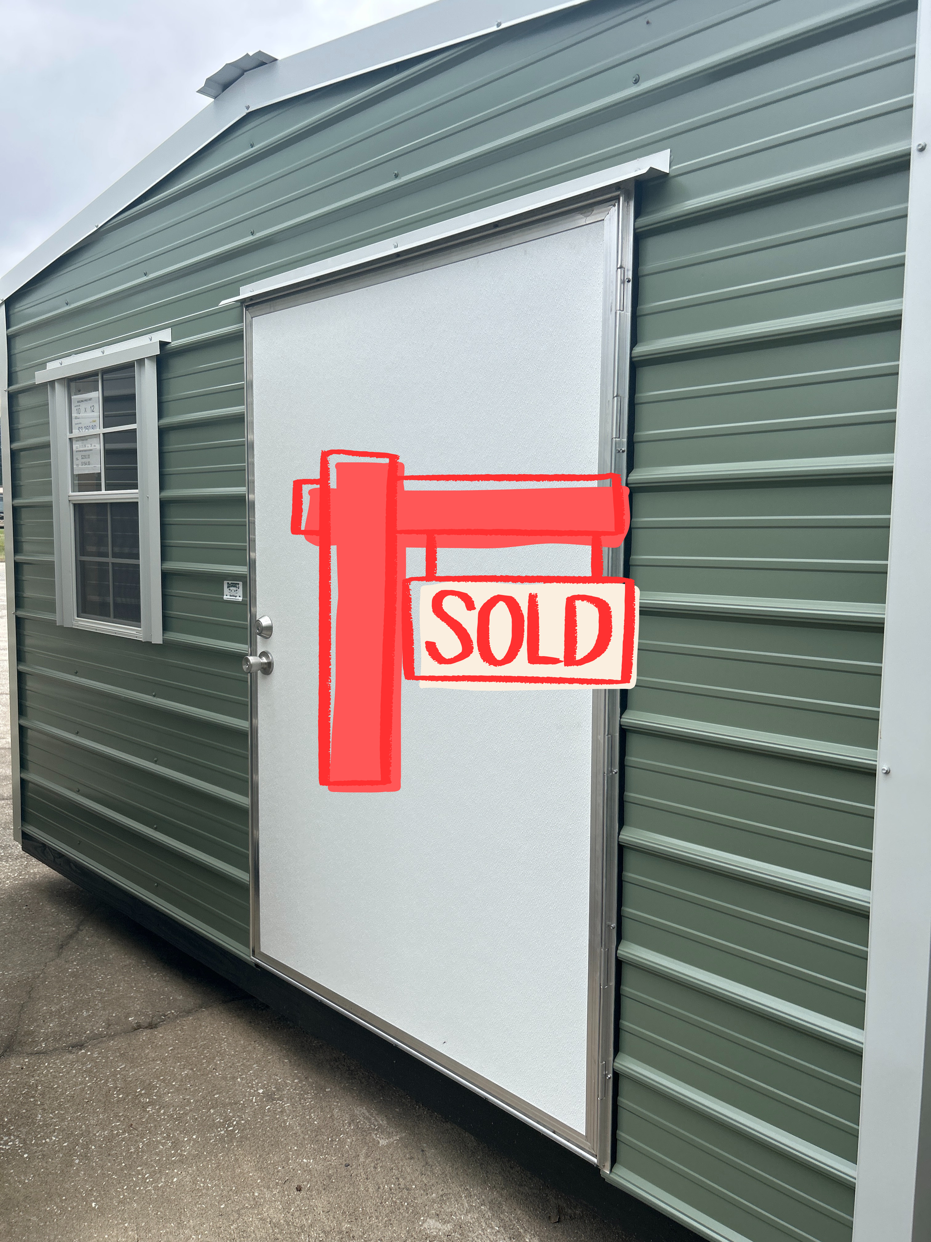 Green metal storage shed with a sliding white door and small window.