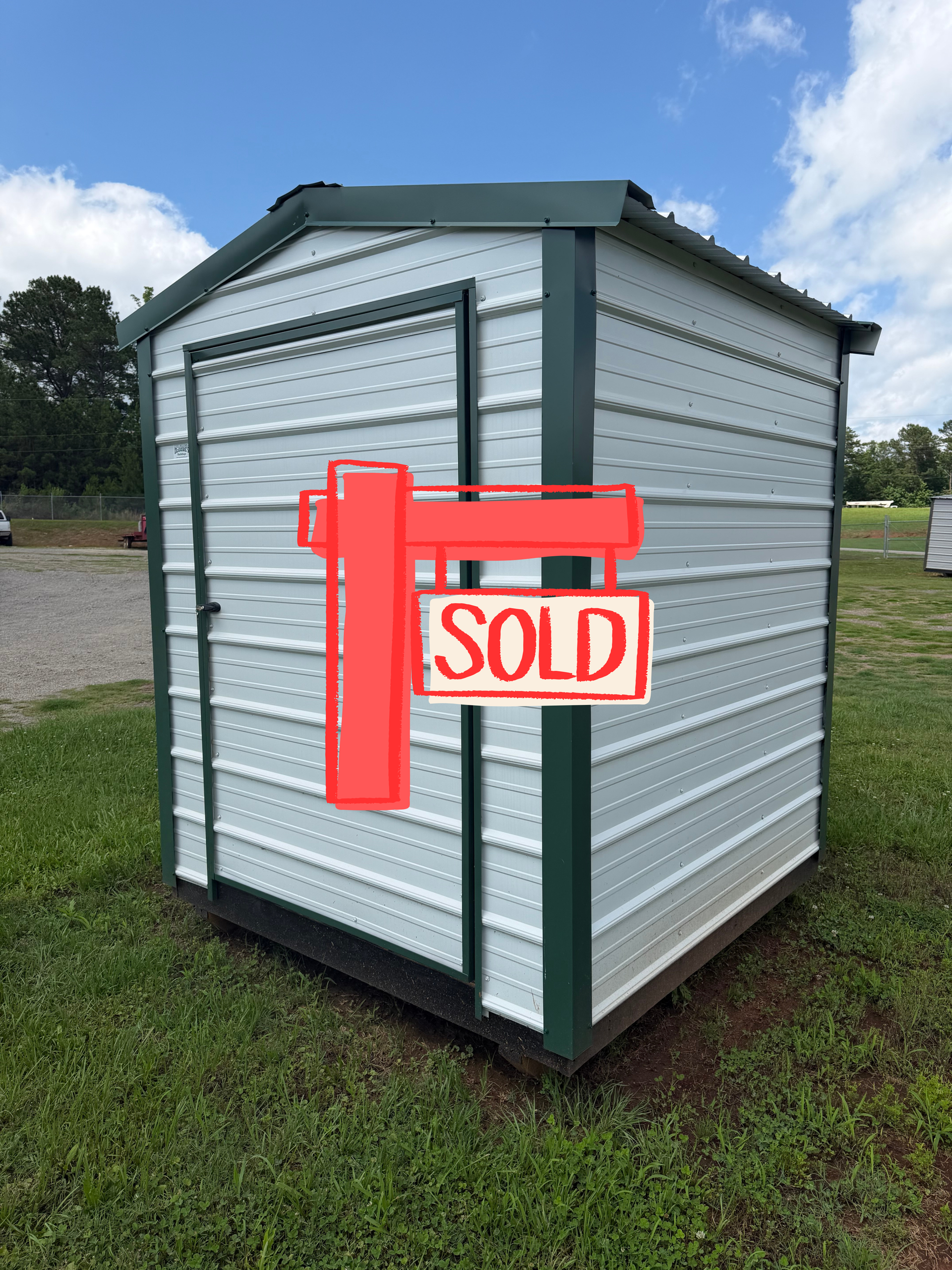 Small gray metal shed with green trim, marked with a red 