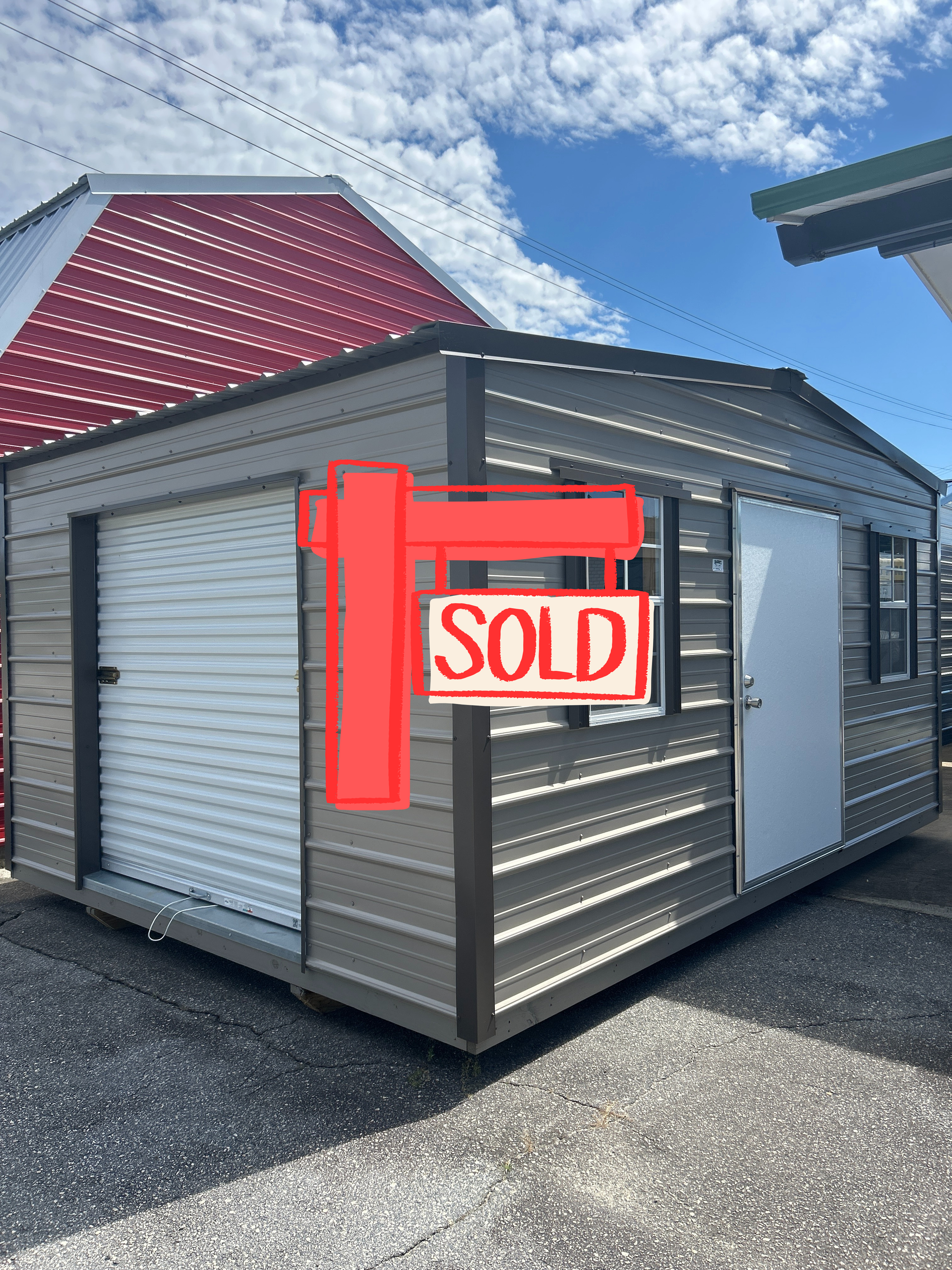 Tan metal shed with a garage door, a window, and a white door, against a blue sky.