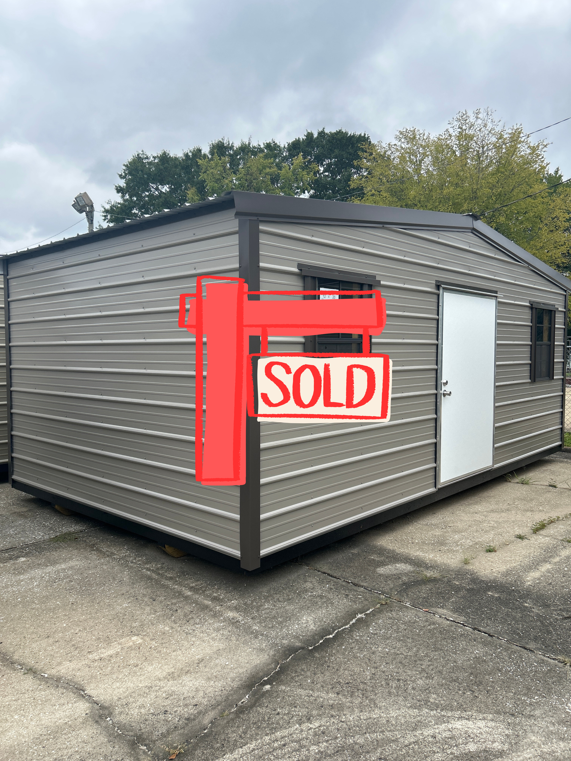 Tan metal shed with brown trim, door, and windows, outdoors.