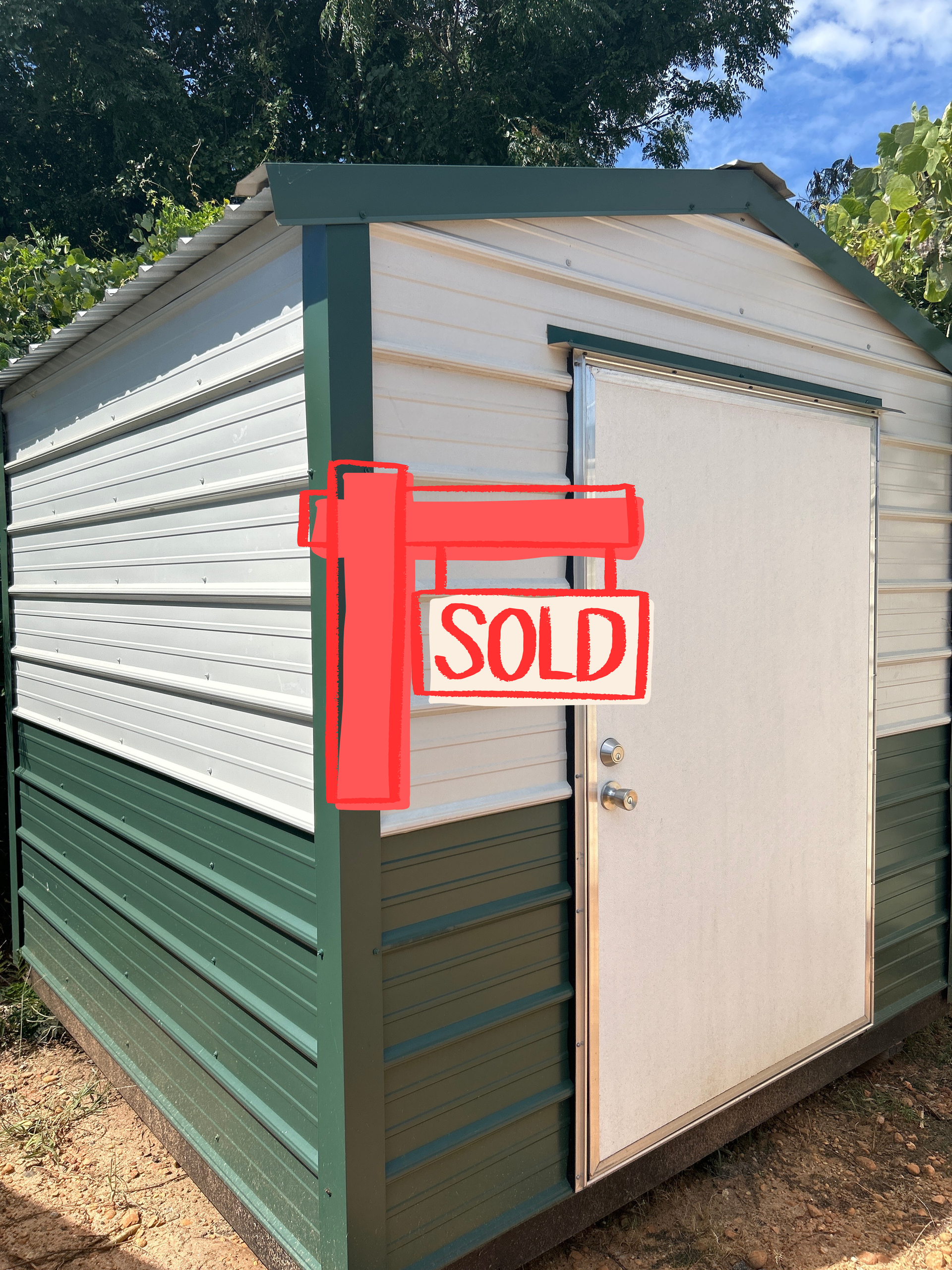 Green and white storage shed with a white door, set outside under a blue sky.