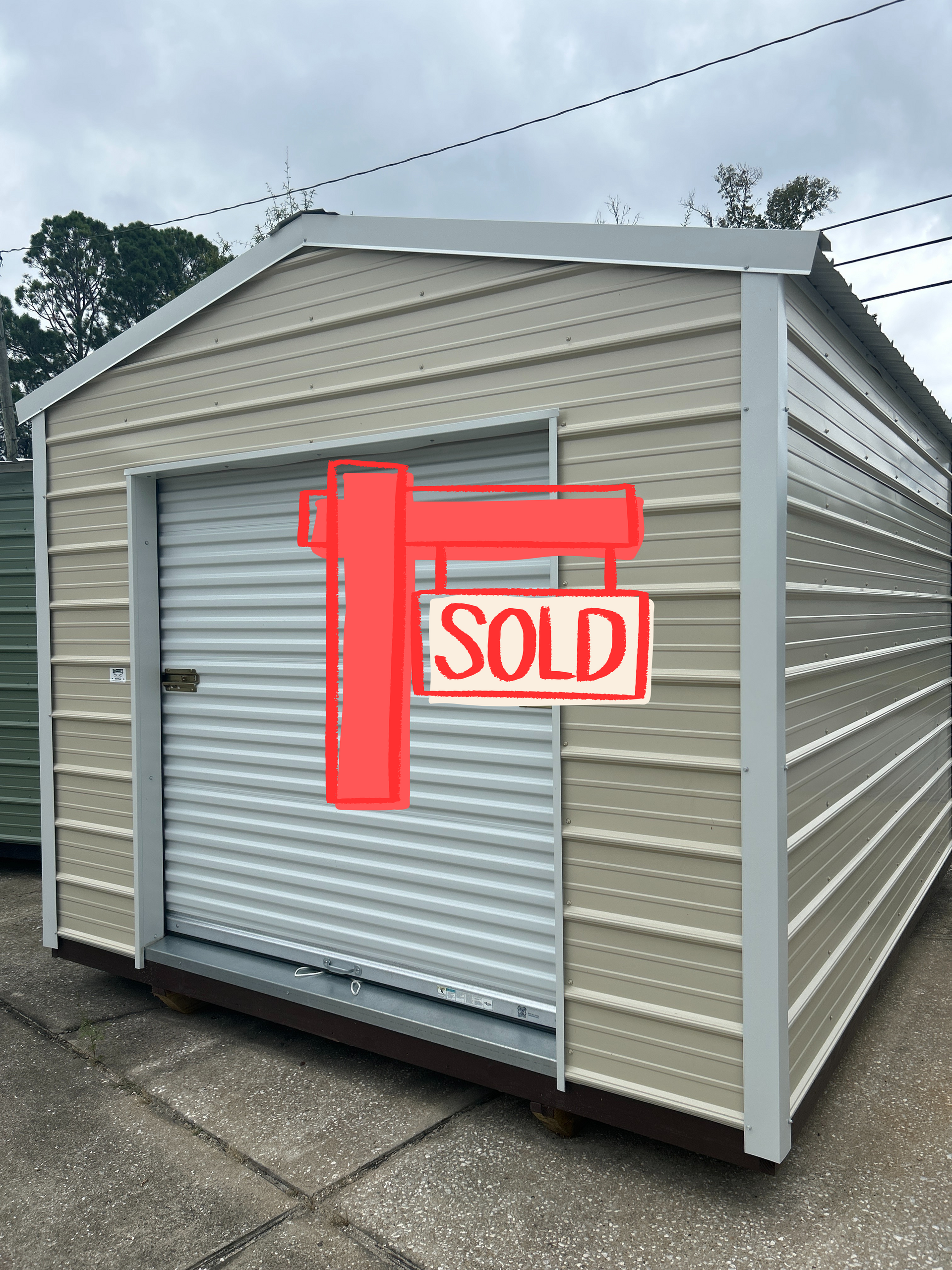 Tan metal storage shed with a roll-up door, sitting on a concrete surface.