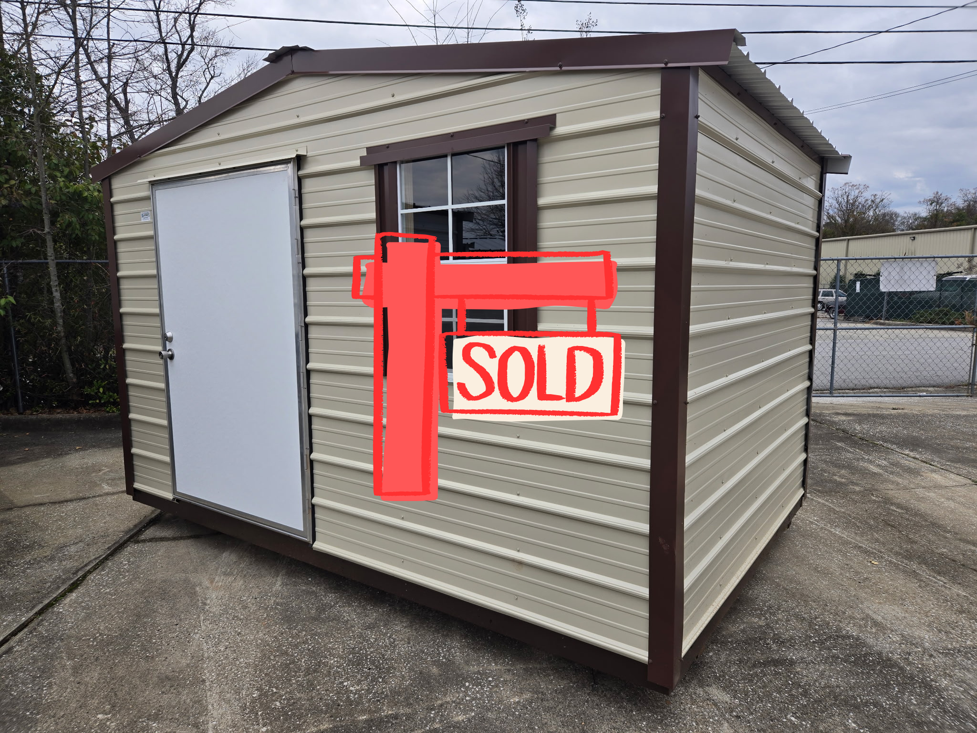 Tan shed with brown trim, door and window, on a concrete surface.