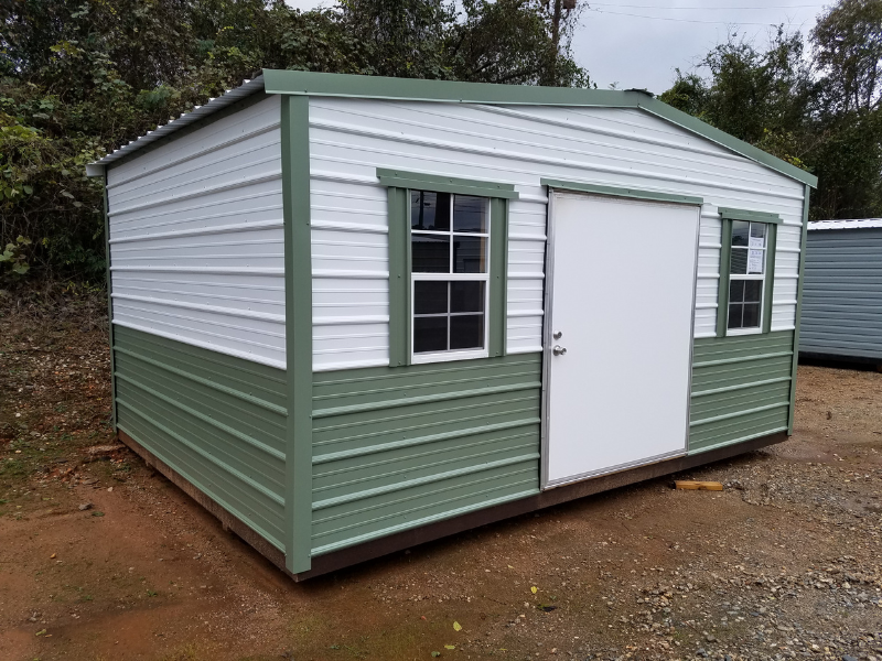 Green and white storage shed with a sliding door and two windows.