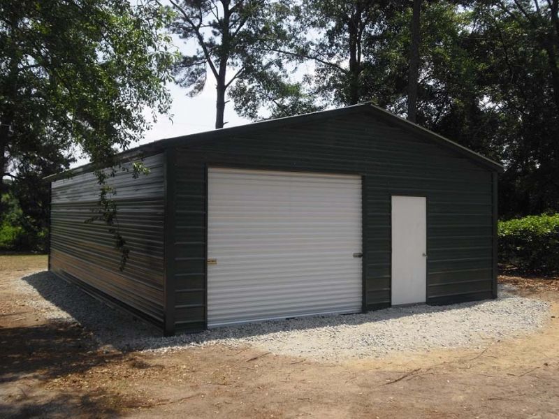 A black garage with a white door and trees in the background