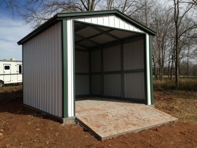 A white and green shed with a trailer in the background