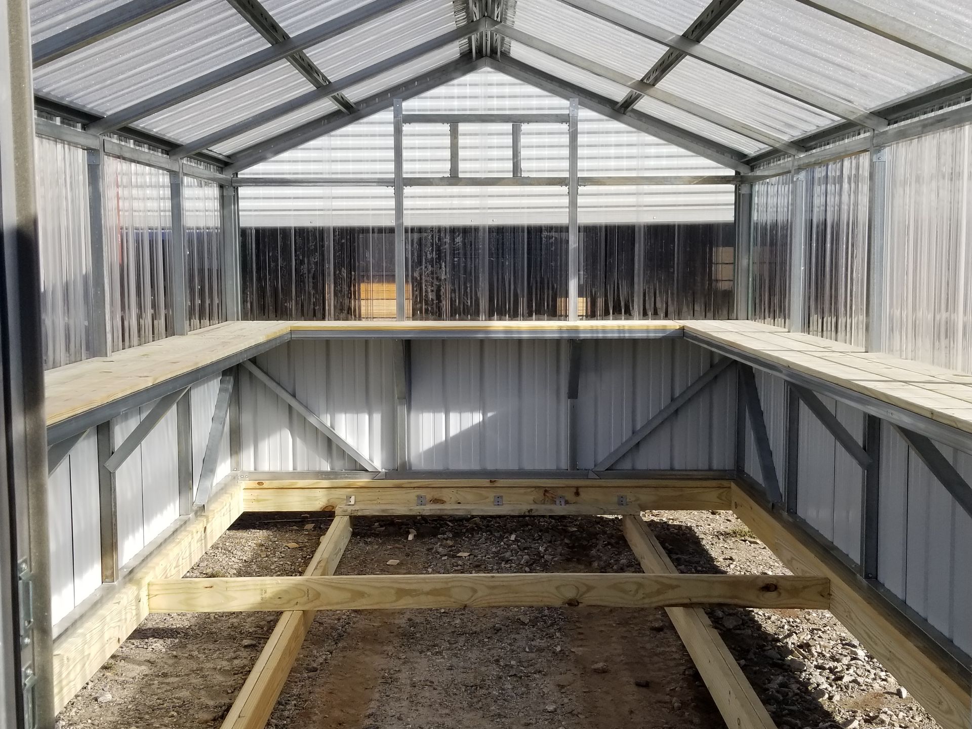 A greenhouse with a wooden floor and a clear roof