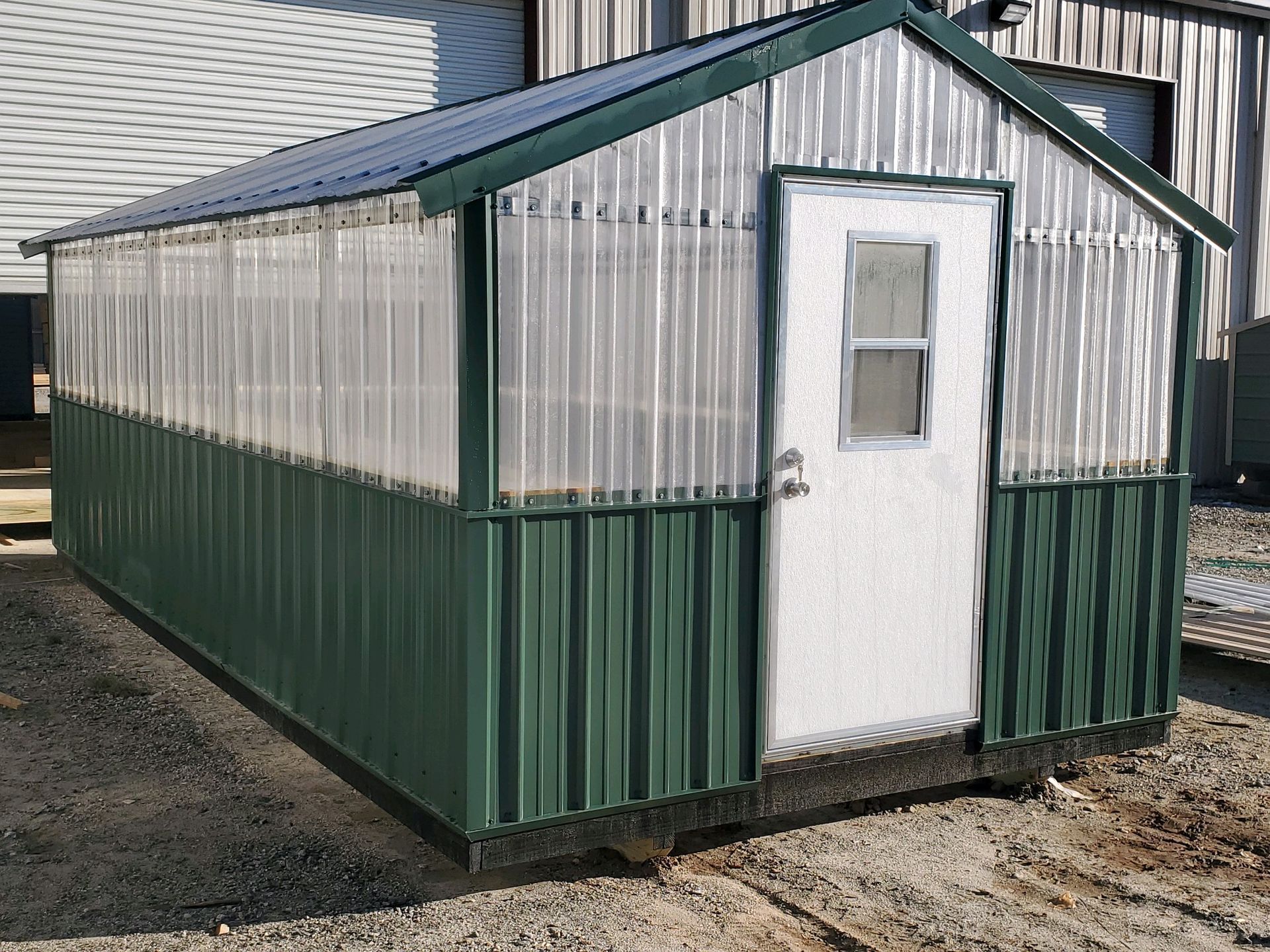 A greenhouse with a white door and a clear roof