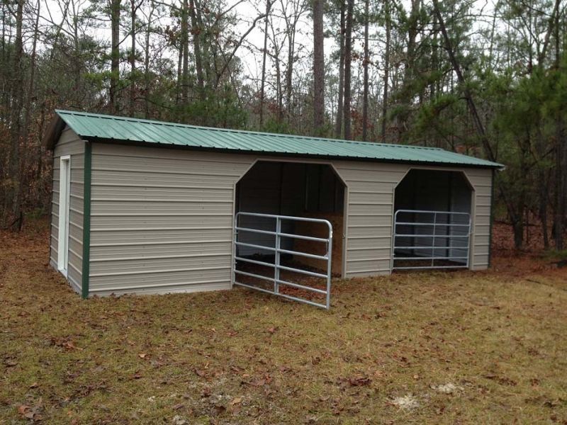 A shed with a green roof is in the middle of a field.