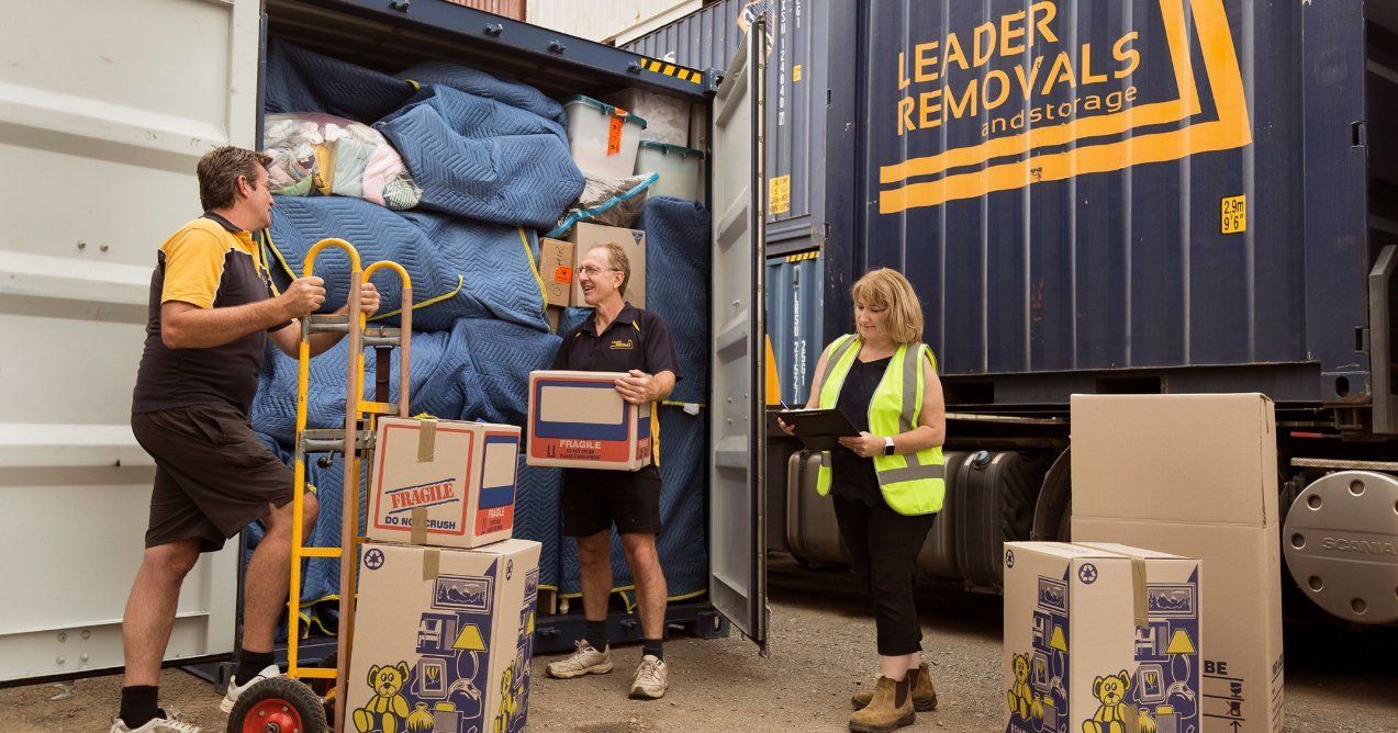 A Group of People Are Loading Boxes Into a Container — Leader Removals & Storage in Mitchell, ACT
