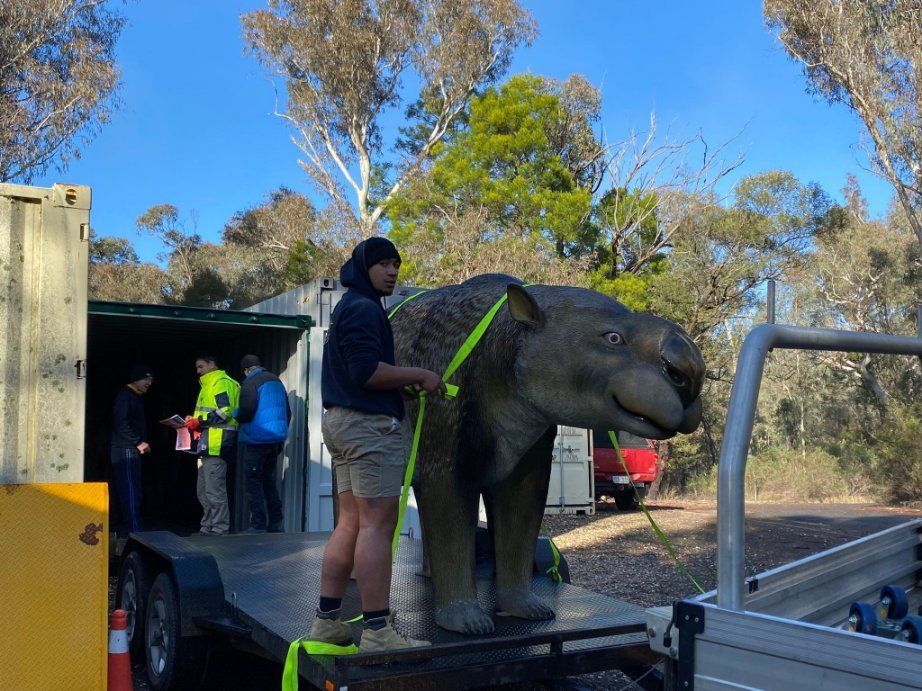 A Man Is Carrying a Statue of A Dinosaur on A Trailer — Leader Removals & Storage in Mitchell, ACT