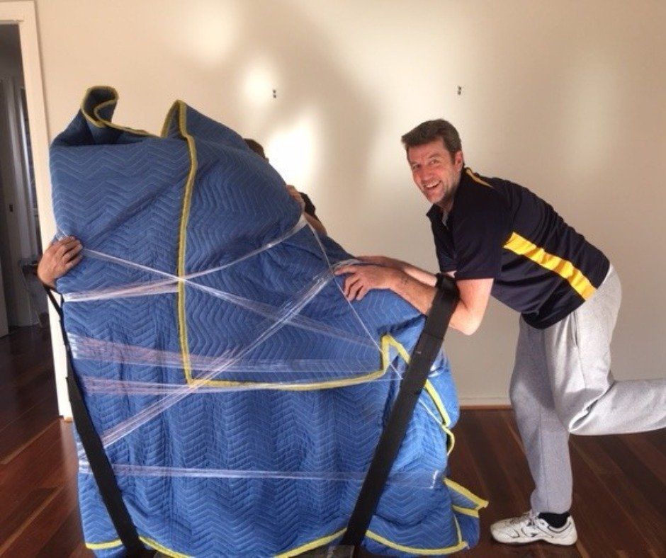 A Man in A Black Shirt Is Carrying a Blue Blanket — Leader Removals & Storage in Albury, NSW