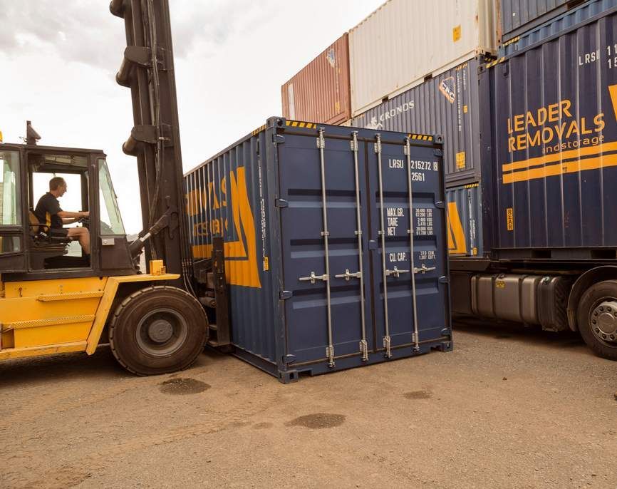 A Forklift is Loading a Blue Shipping Container Into a Truck — Leader Removals & Storage in Canberra, ACT