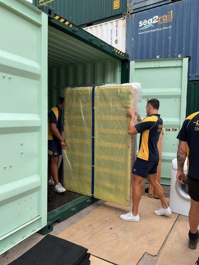 A Man is Carrying a Mattress Into a Shipping Container — Leader Removals & Storage in Mitchell, ACT