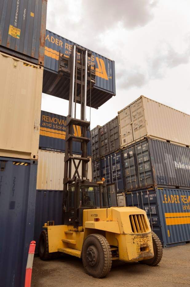 A Yellow Forklift is Moving a Stack of Shipping Containers — Leader Removals & Storage in Port Macquarie, NSW