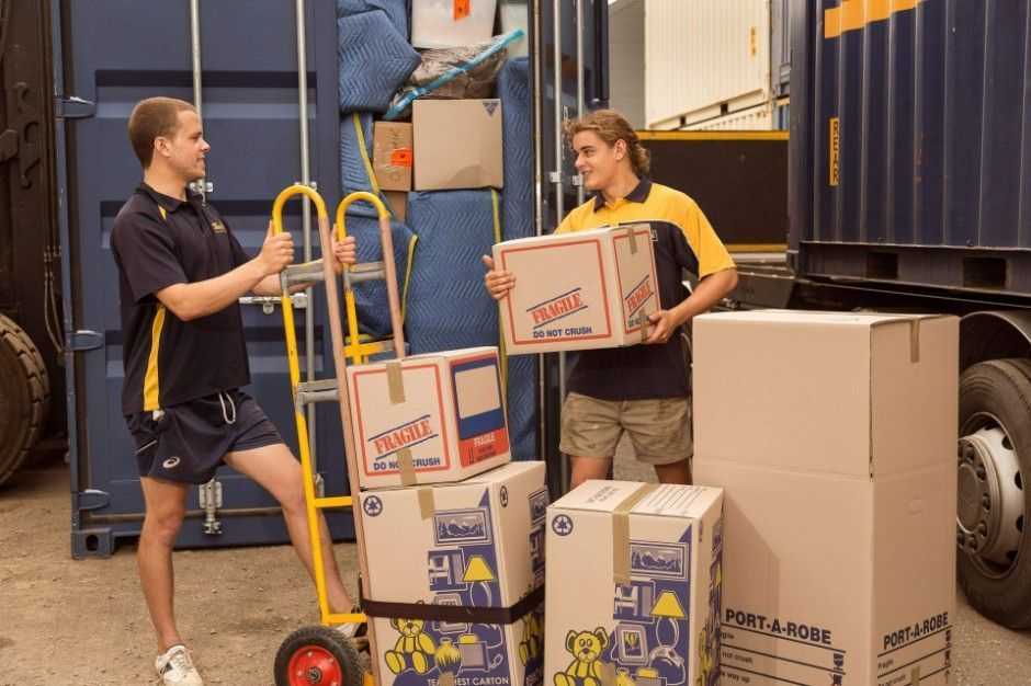 Two Men Are Carrying Boxes in Front of a Moving Truck — Leader Removals & Storage in Newcastle, NSW