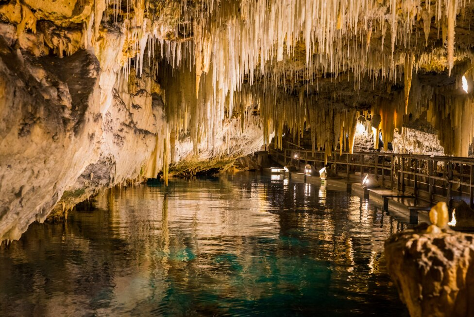 A cave filled with water and icicles hanging from the ceiling.