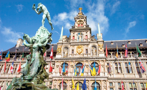 green satue in front of a building with colorful flags in the portico