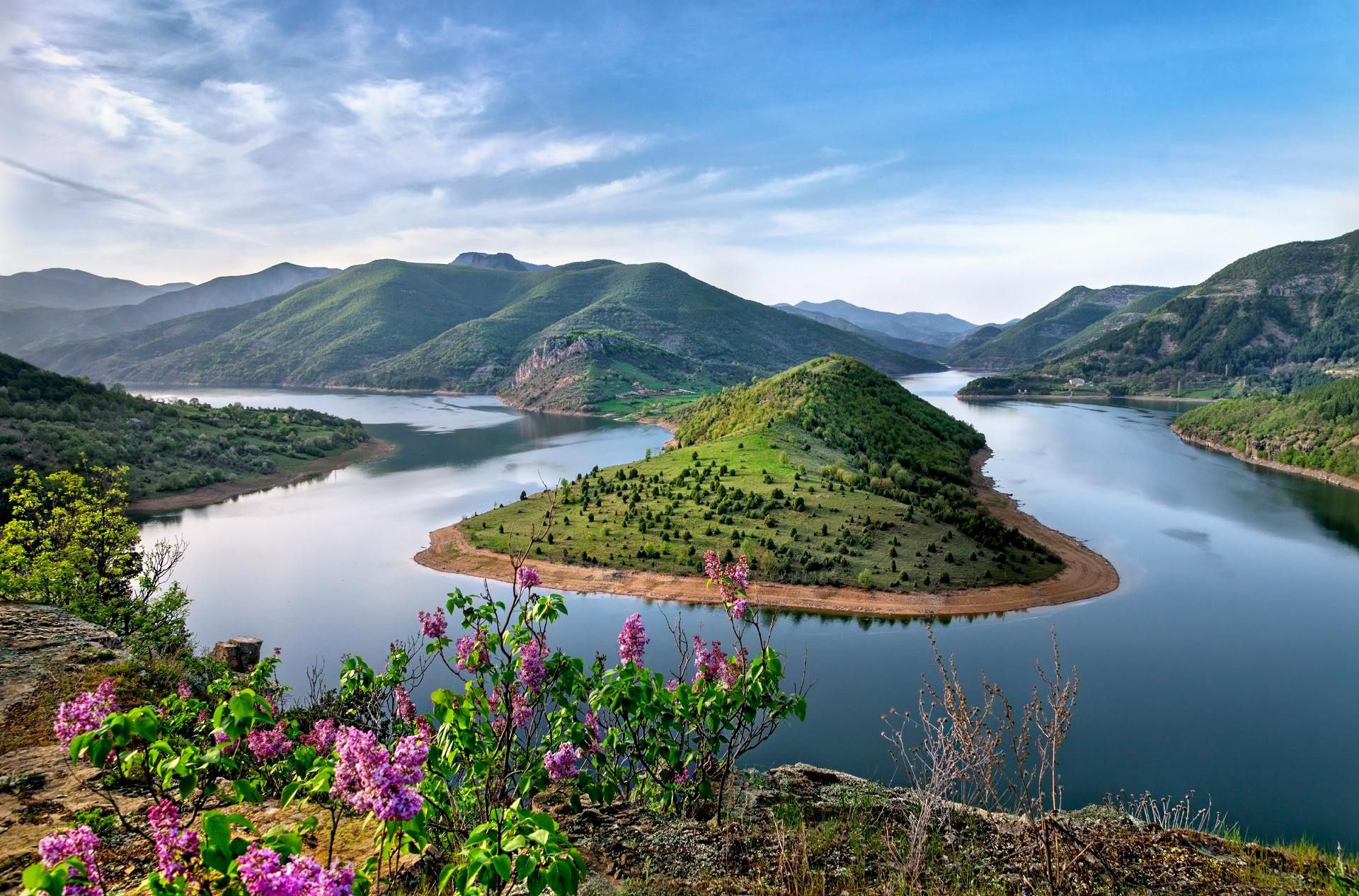 There is a small island in the middle of the lake surrounded by mountains.