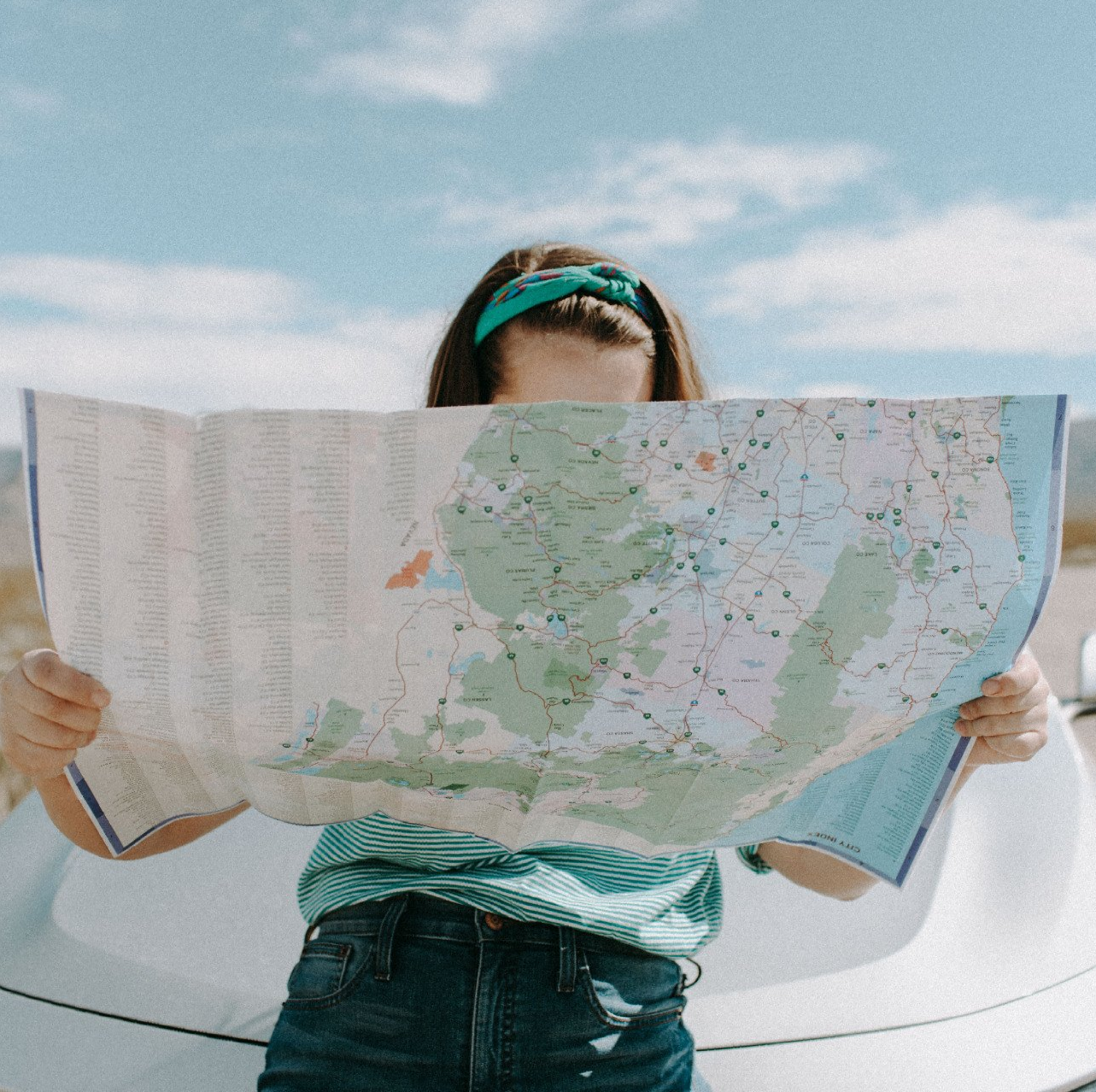 A woman is holding a map in front of her face