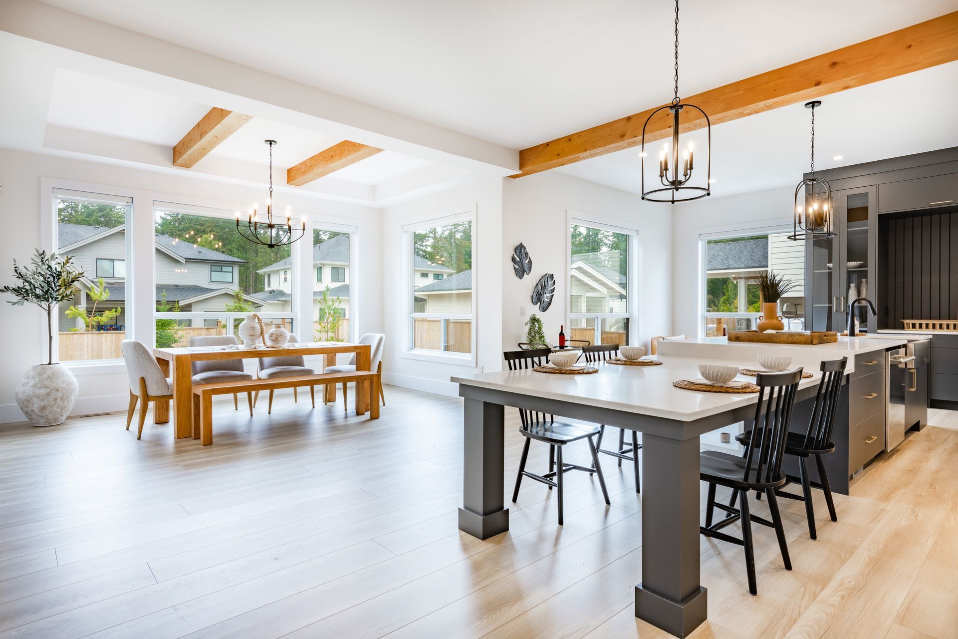 Open-plan kitchen and dining area with large windows, light wood floors, and neutral tones.