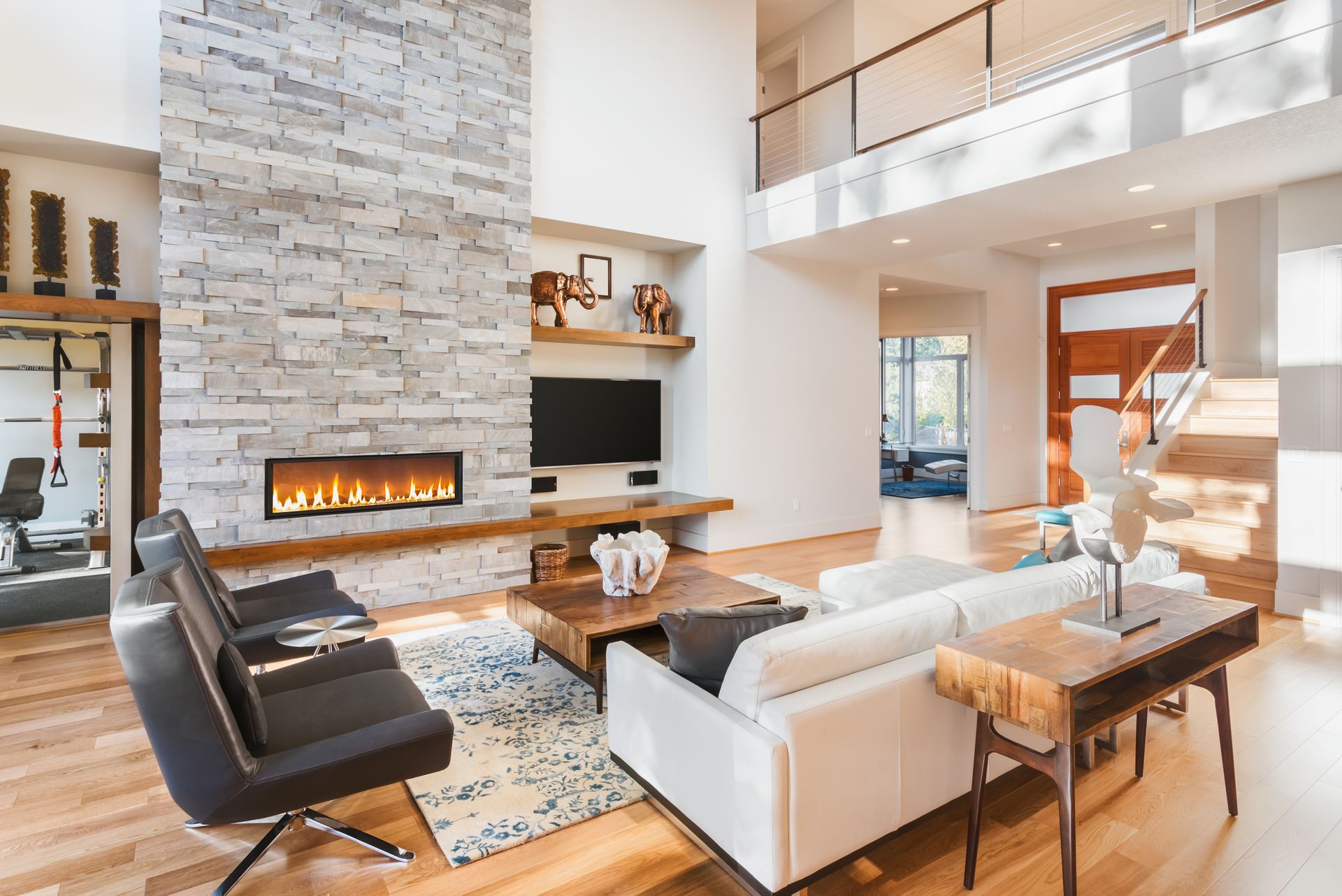 Modern living room with fireplace, white sofa, wooden floors, and a mezzanine.