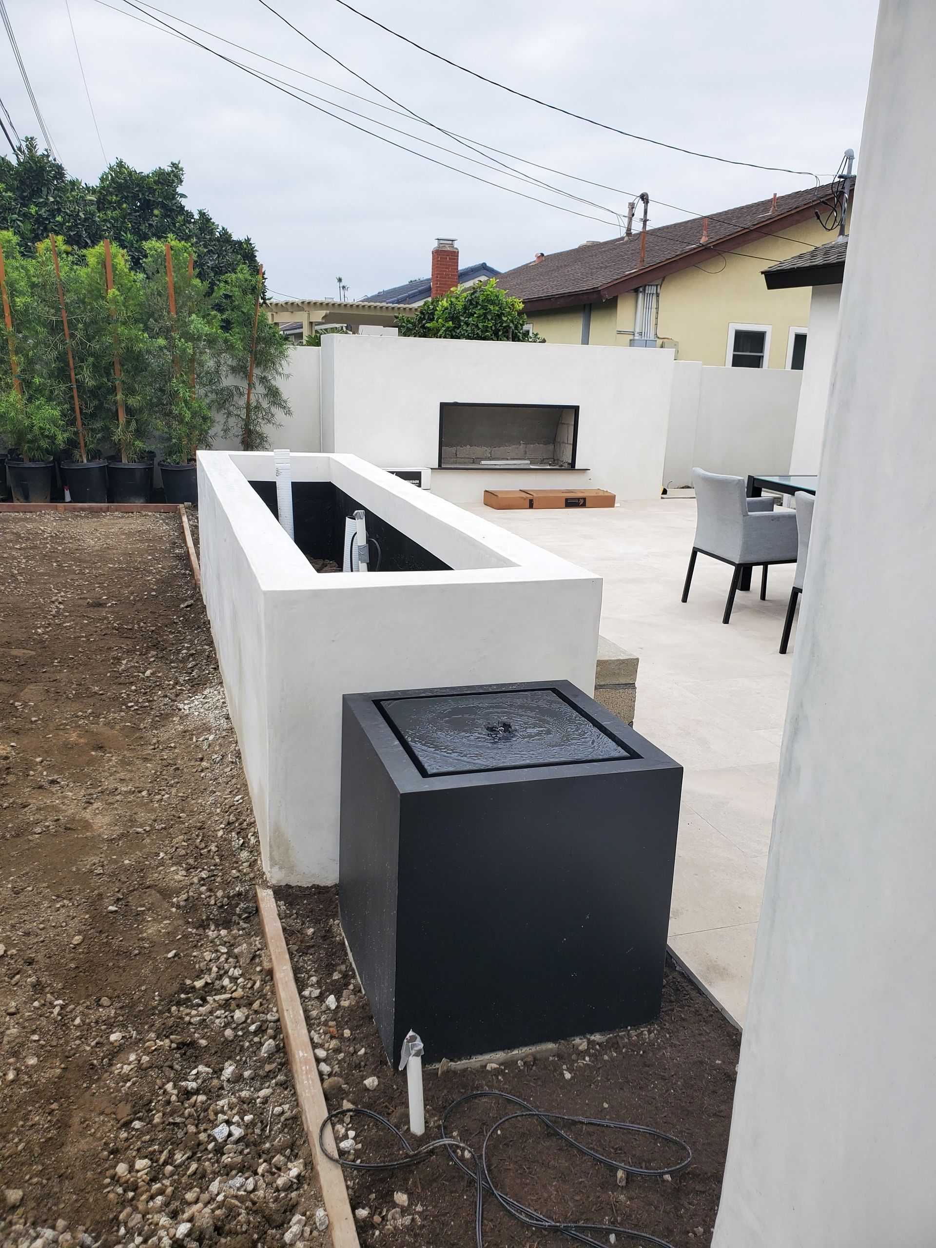 Outdoor patio with white walls, built-in fireplace, and a water feature with a black square base.