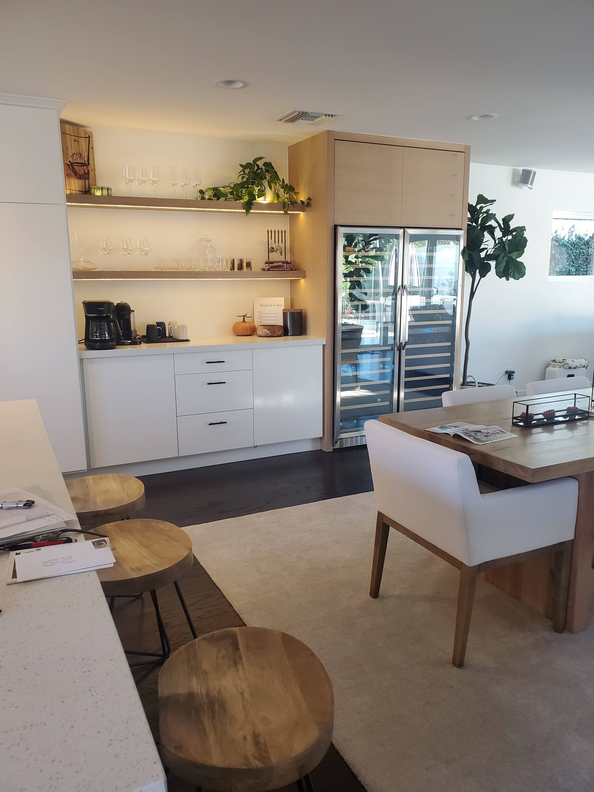 Interior with bar, fridge, and dining area. White cabinetry, wood accents, and plants.