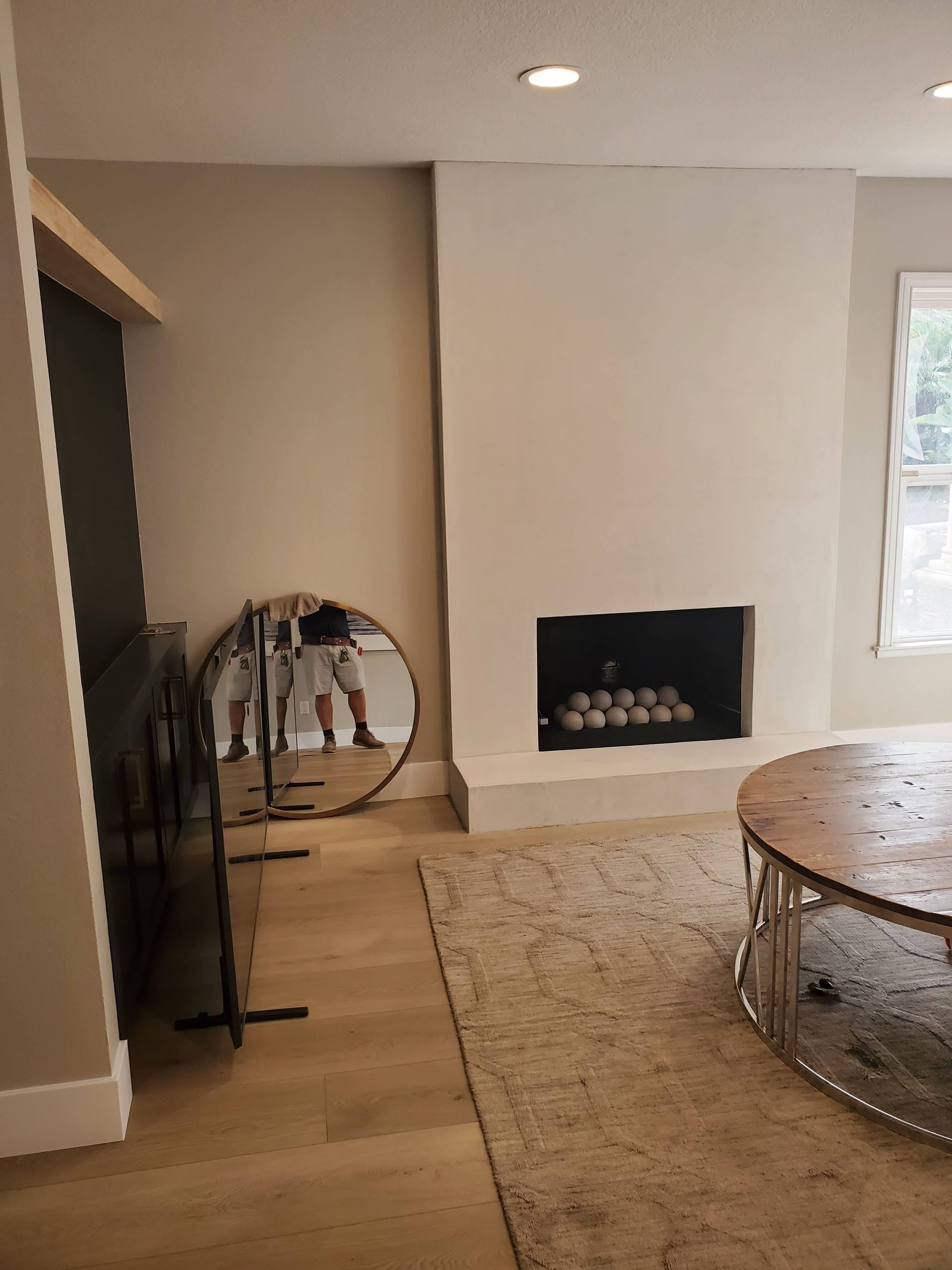 Living room with fireplace, round mirror, rug, and coffee table.