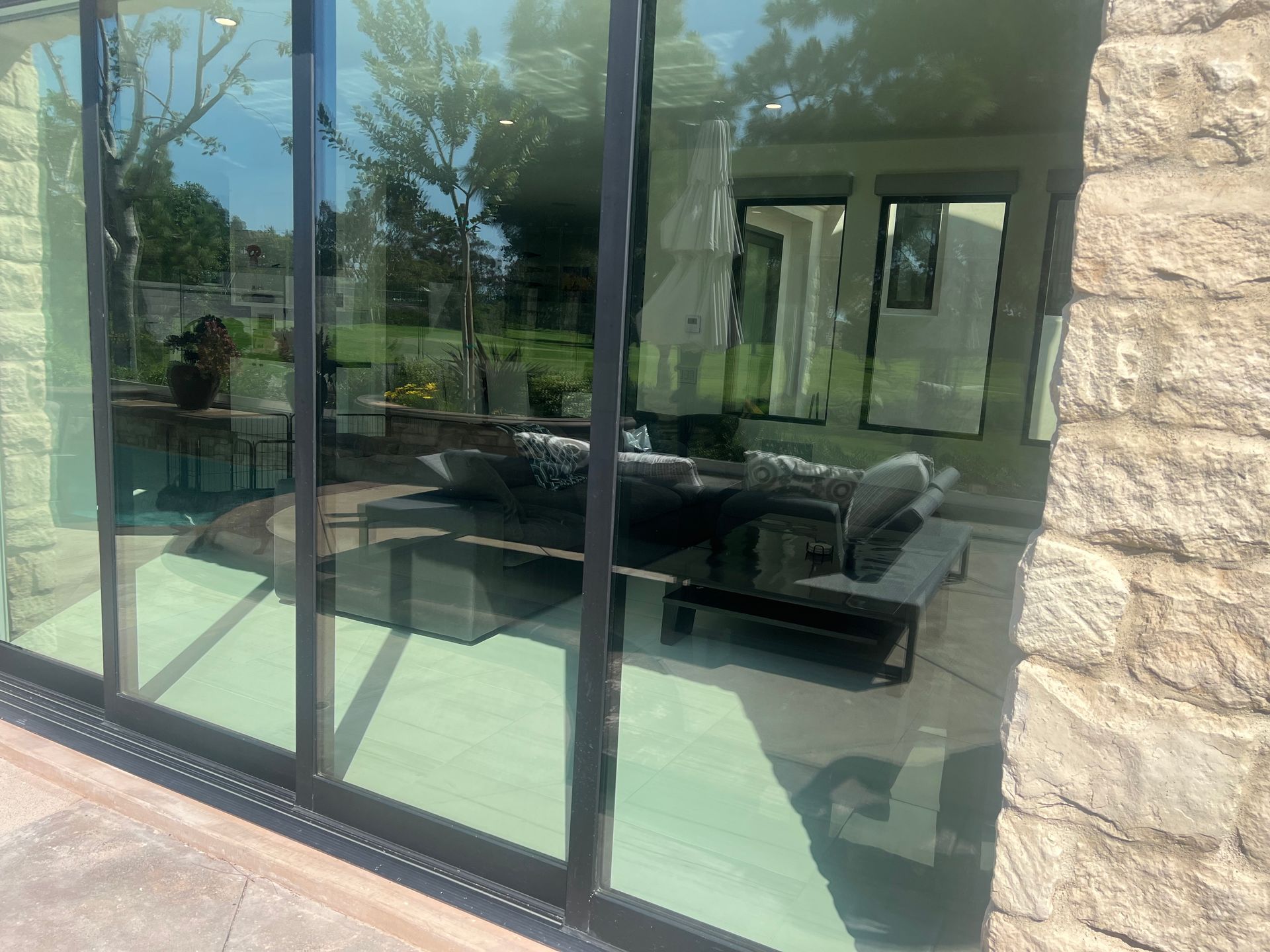 Sliding glass doors overlooking a patio with outdoor furniture, stone wall on the right.