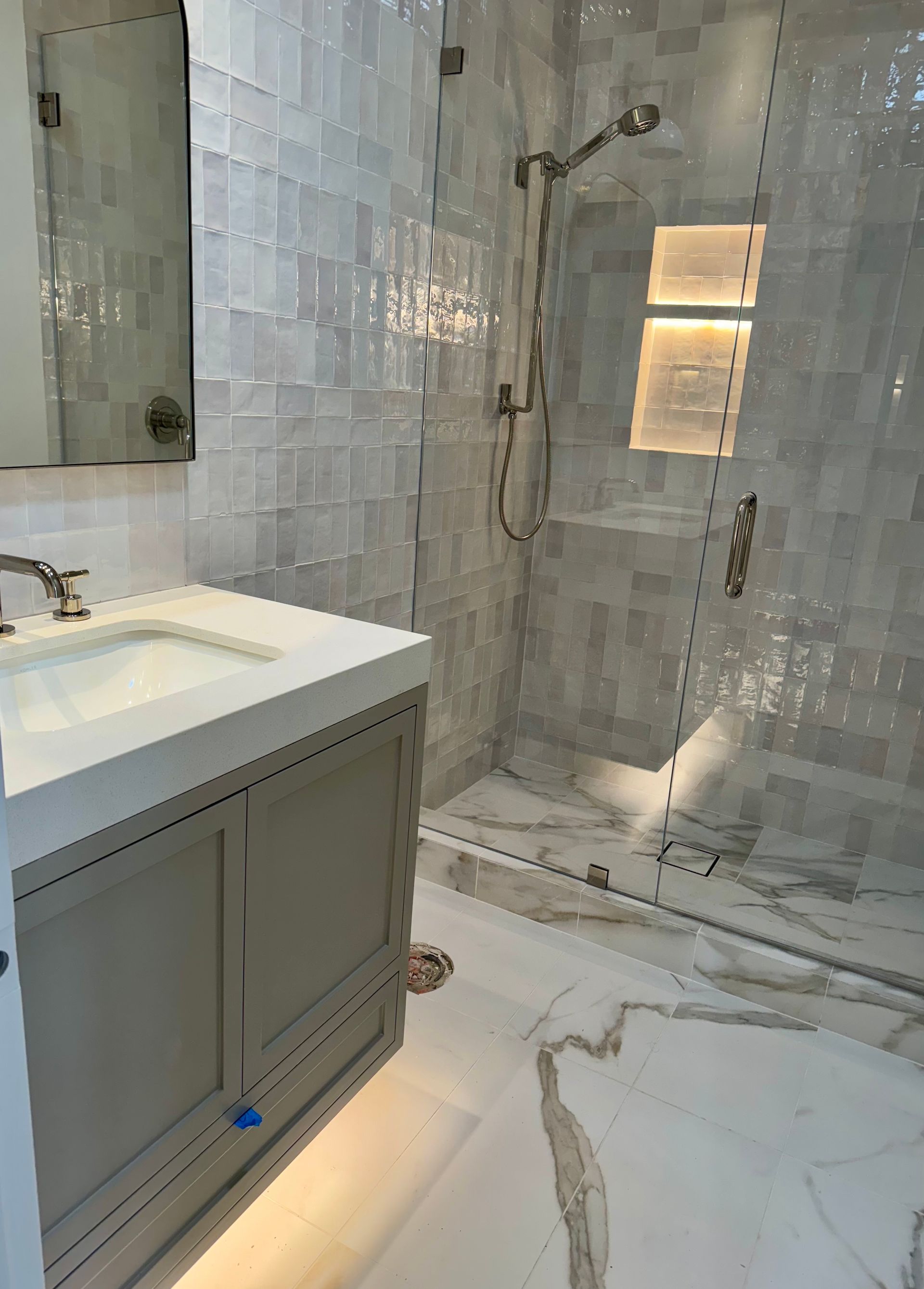 Bathroom with gray vanity, marble floor, tiled shower, and glass enclosure.