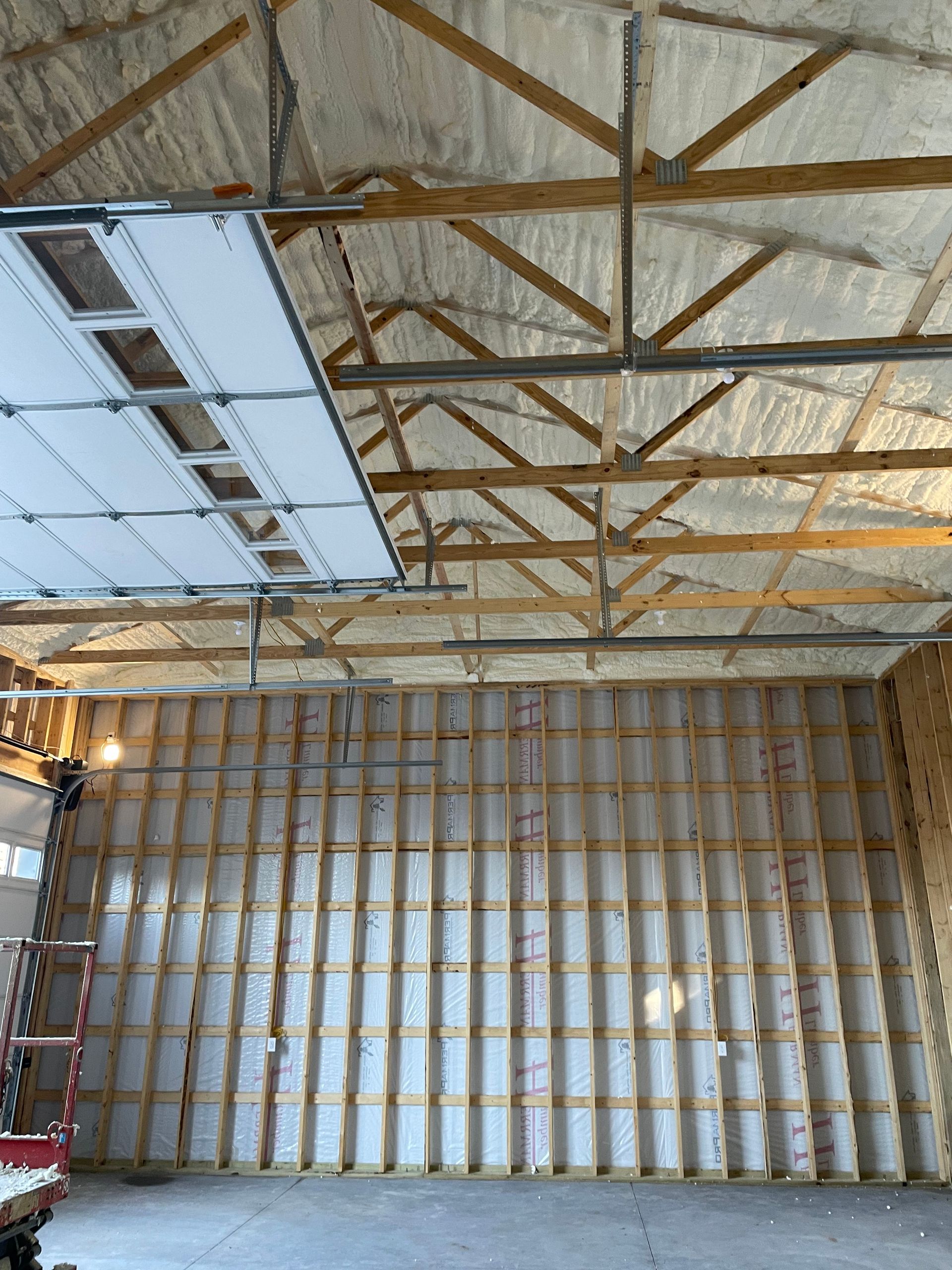 A garage with a garage door open and a lot of insulation on the walls.