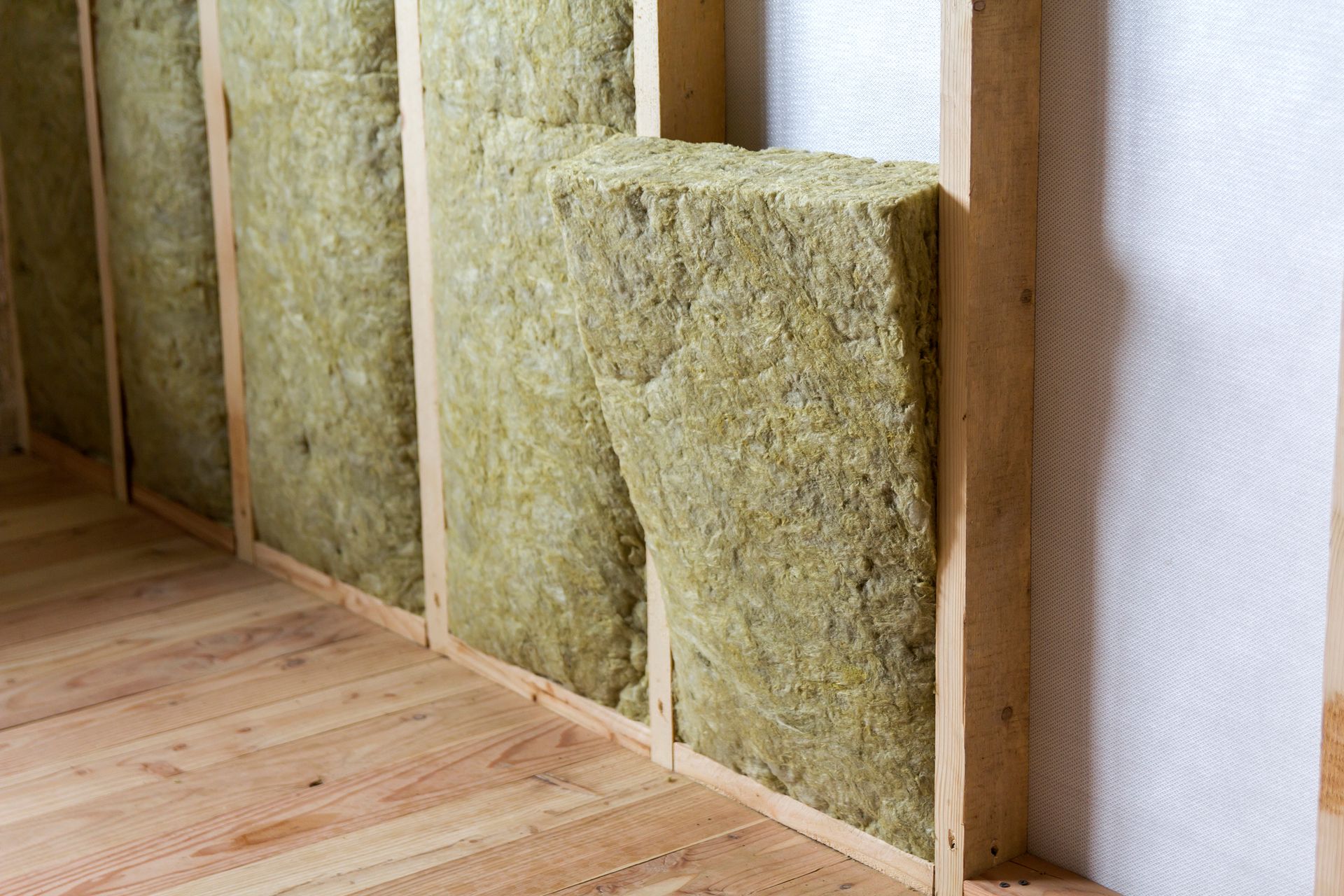 A room with a wooden floor and a wall with rockwool insulation.