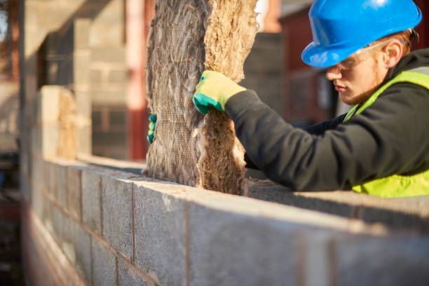 A construction worker is working on a brick wall.